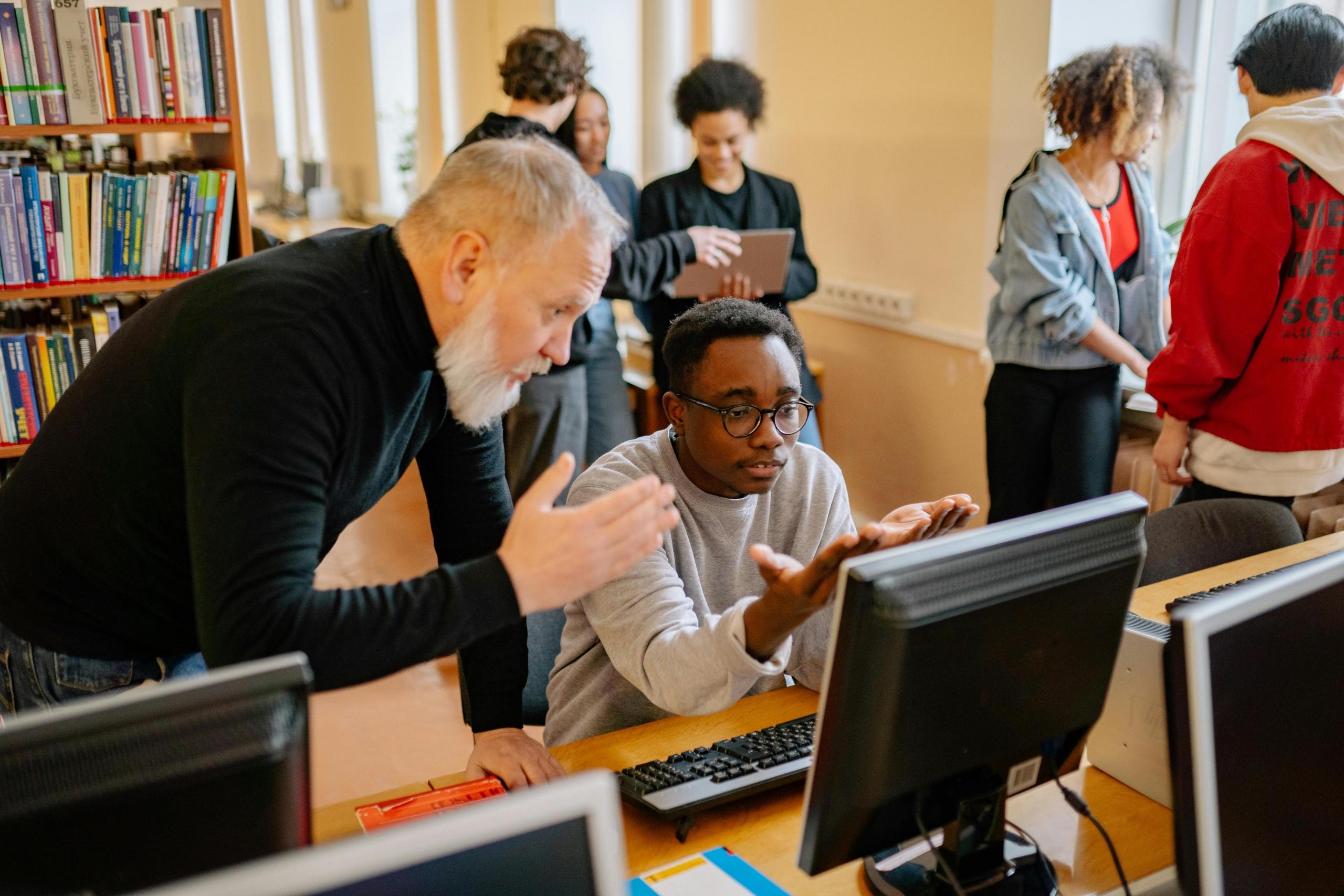 A professor teaching a student something on the computer