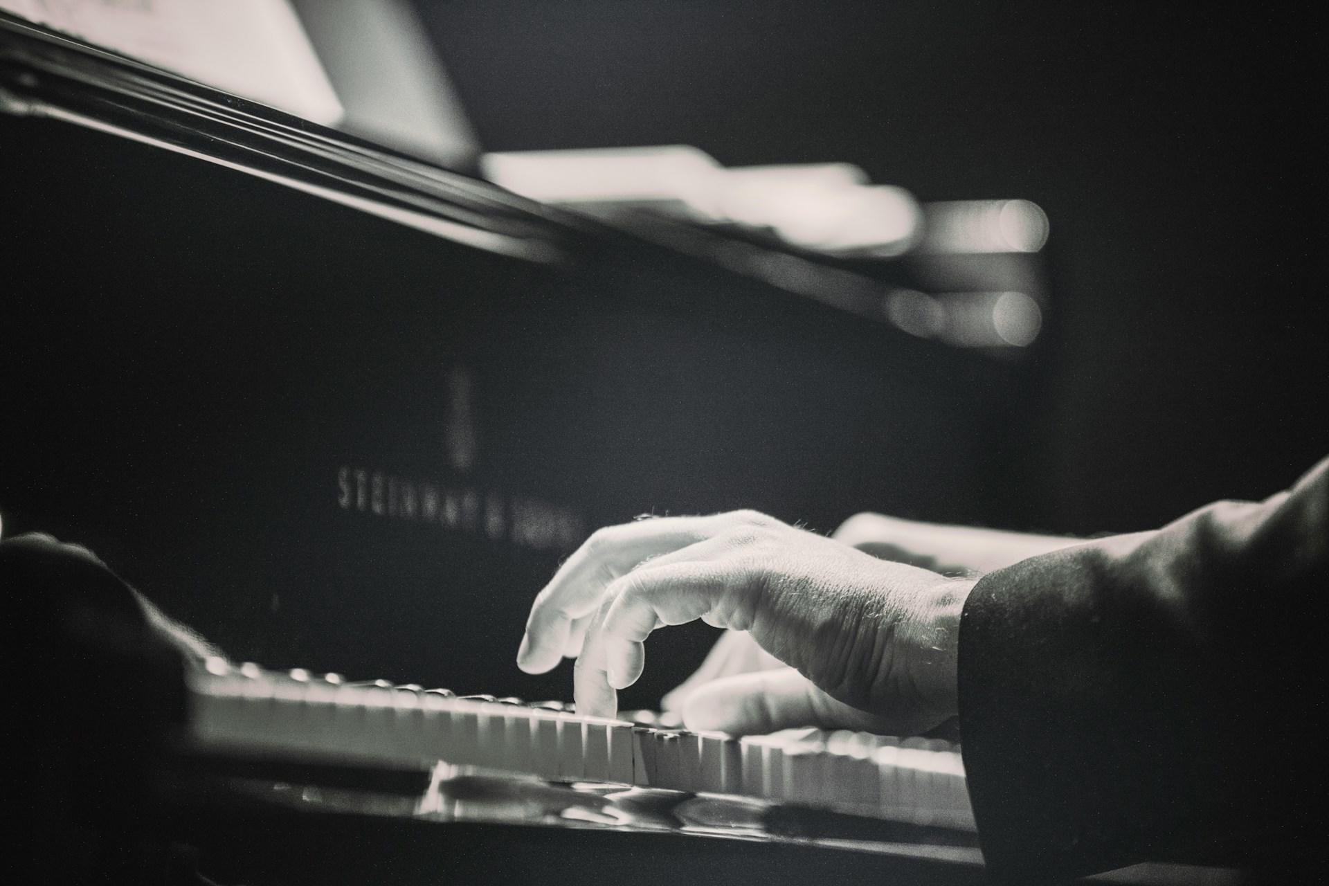 A black and white photo of a pianist's hands playing the piano.