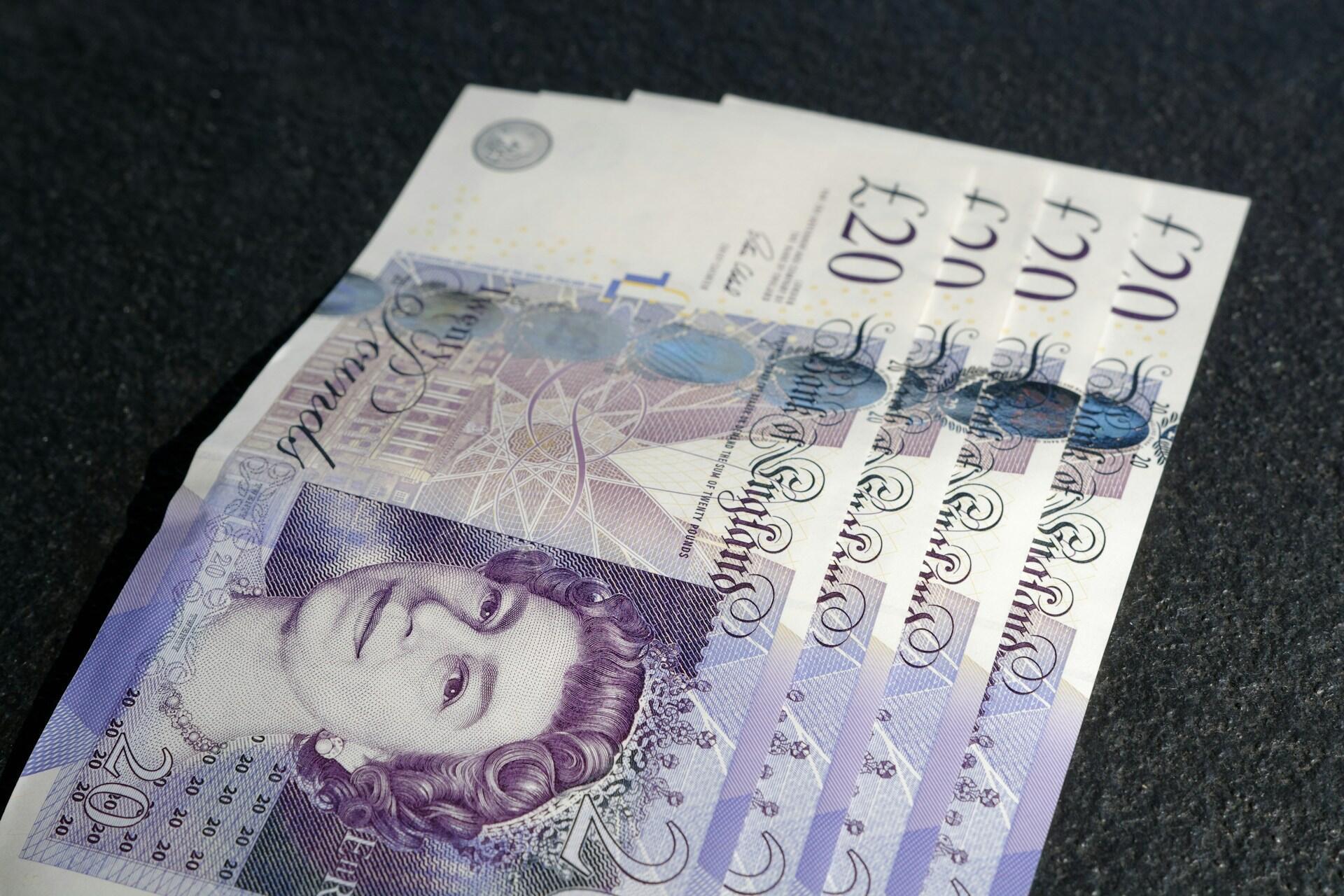 British twenty-pound notes arranged on a dark surface.