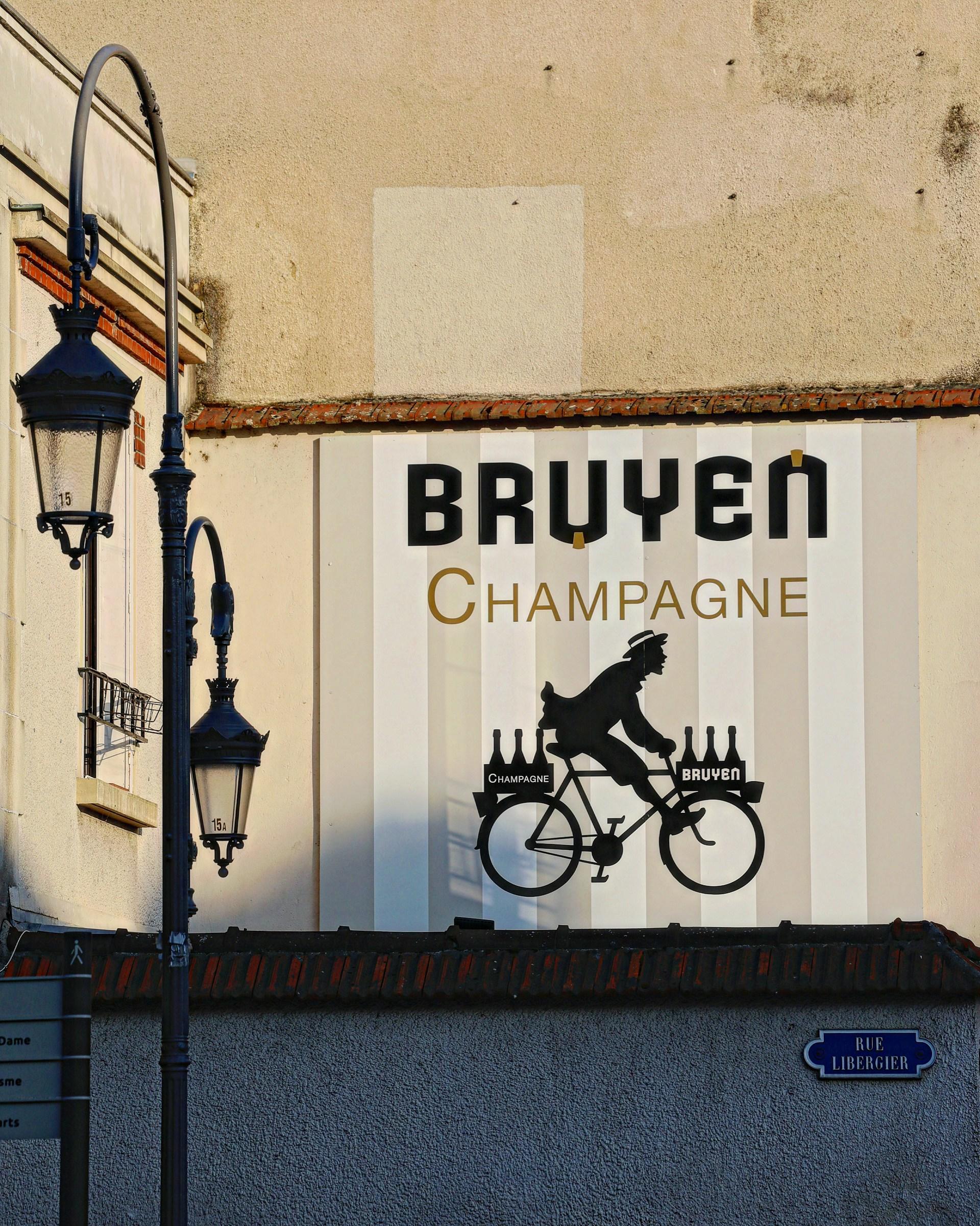 A sign advertising champagne delivered by bike on a brown building. 