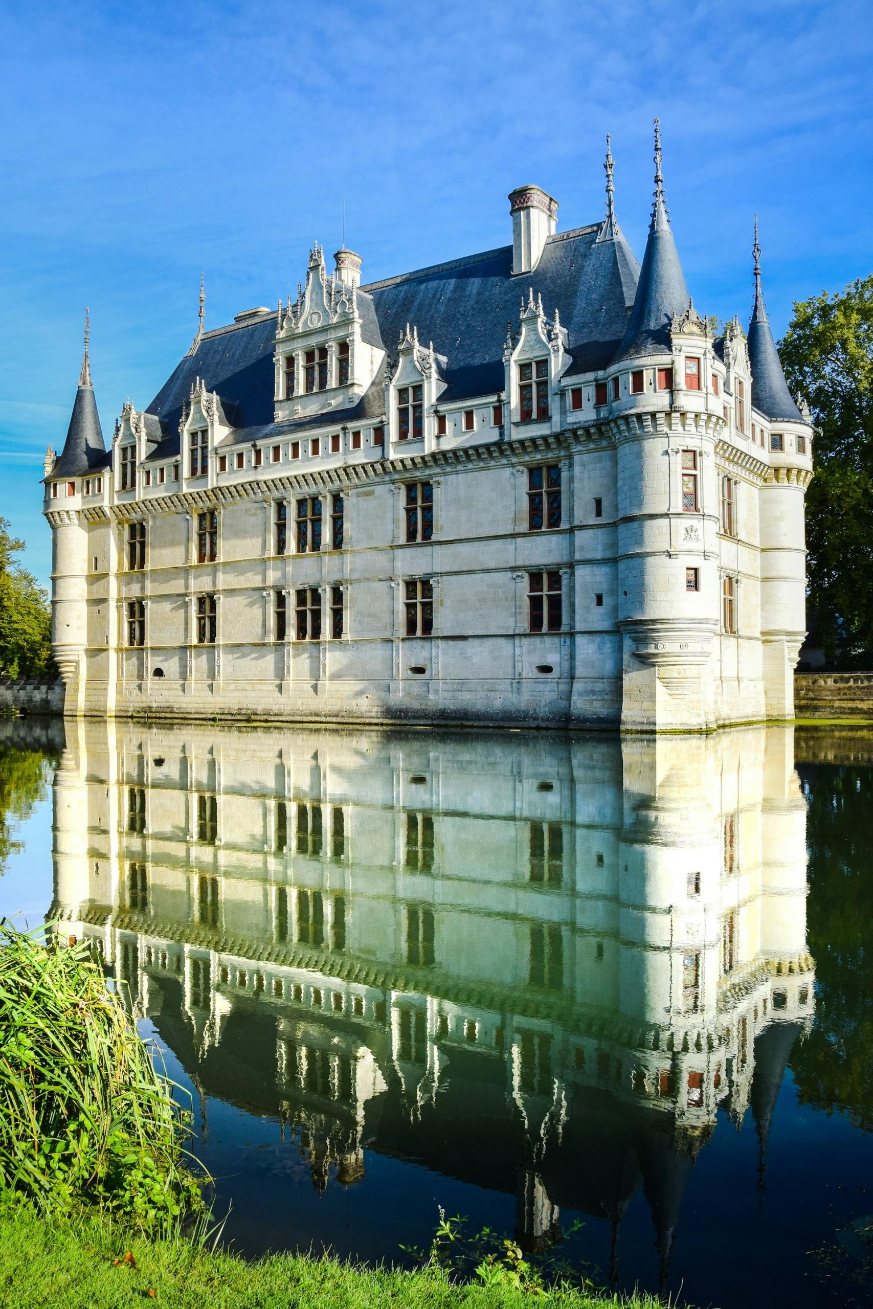 A large white building with a black roof and a moat.