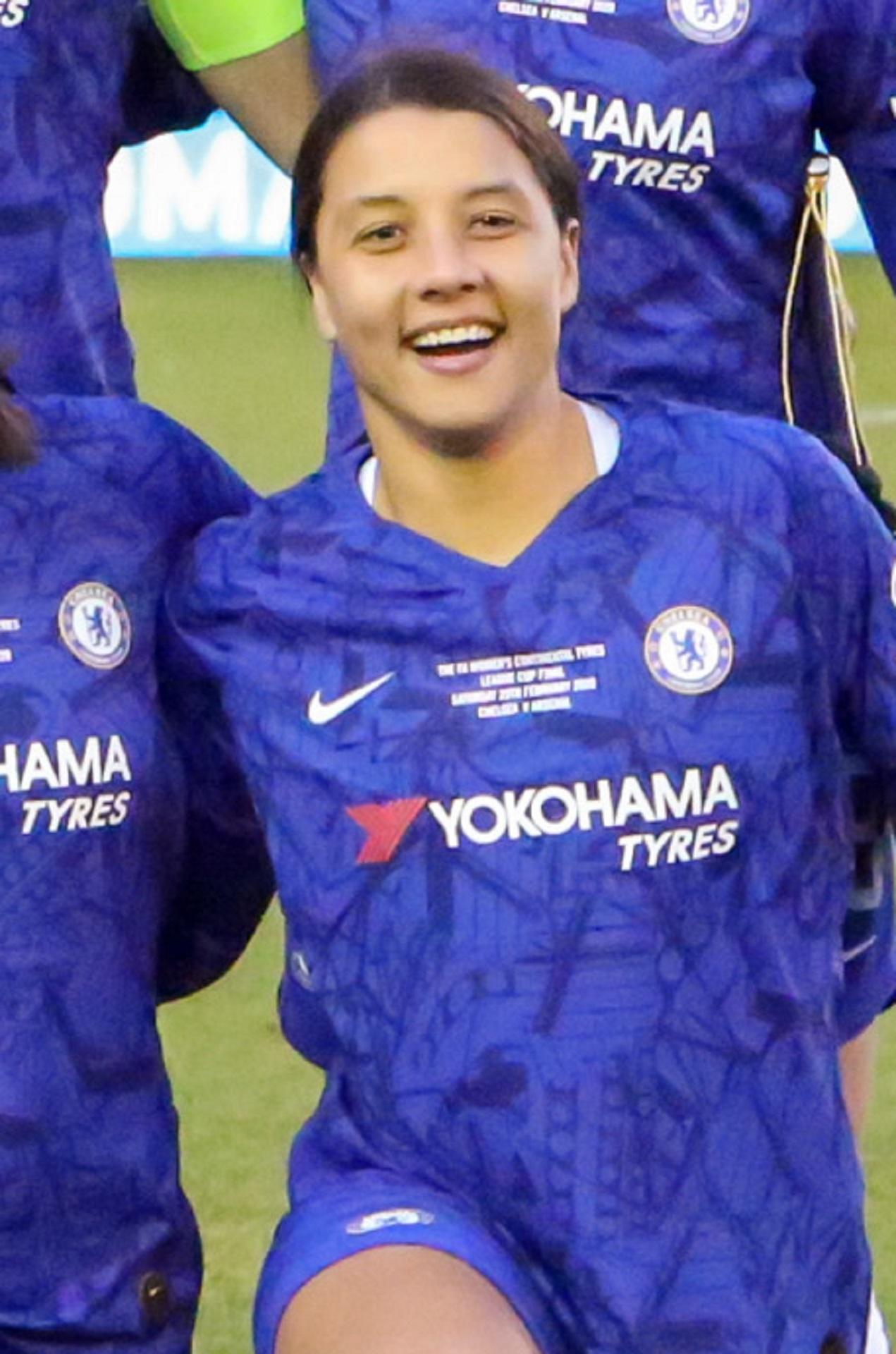 A woman wears a blue jersey and smiles.