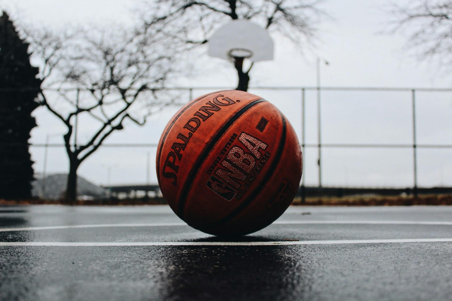 Basketball on rainy outdoor court.