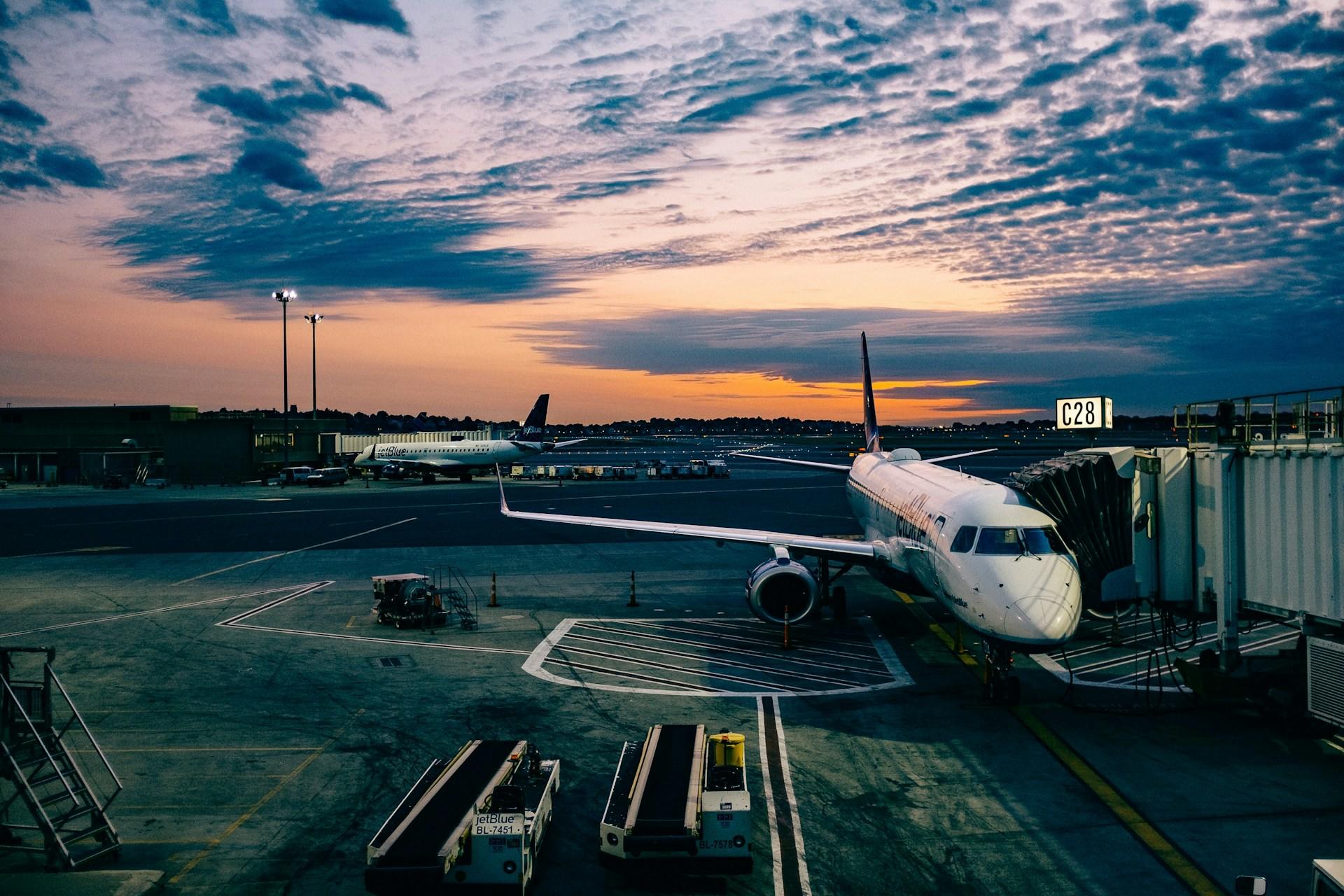 A white airplane docked at a passenger ramp at sunset. 