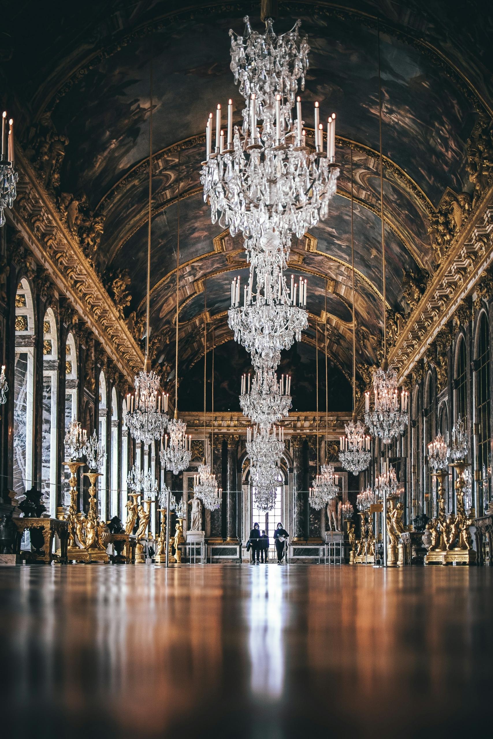 A grand indoor hall with chandeliers hanging from the arched ceiling.