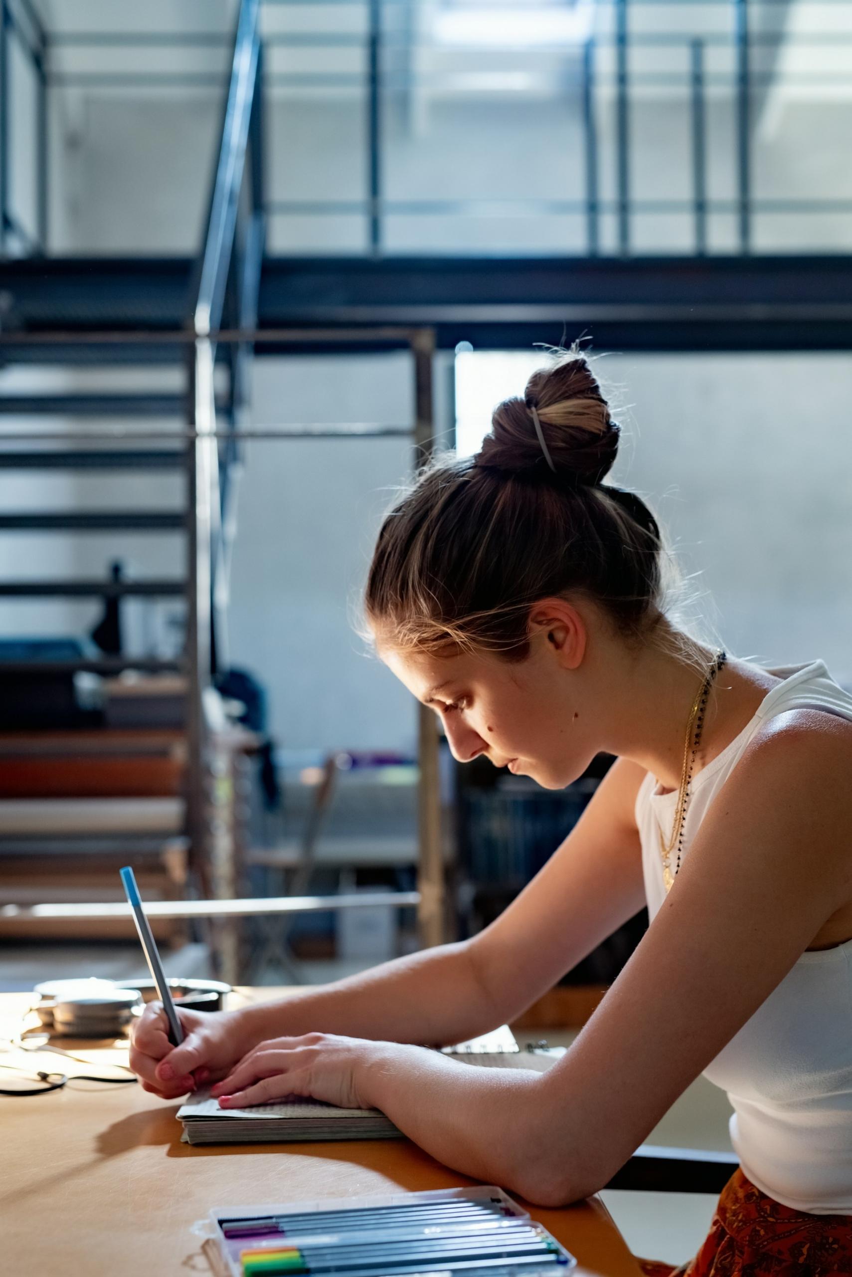 A person at a table, writing.