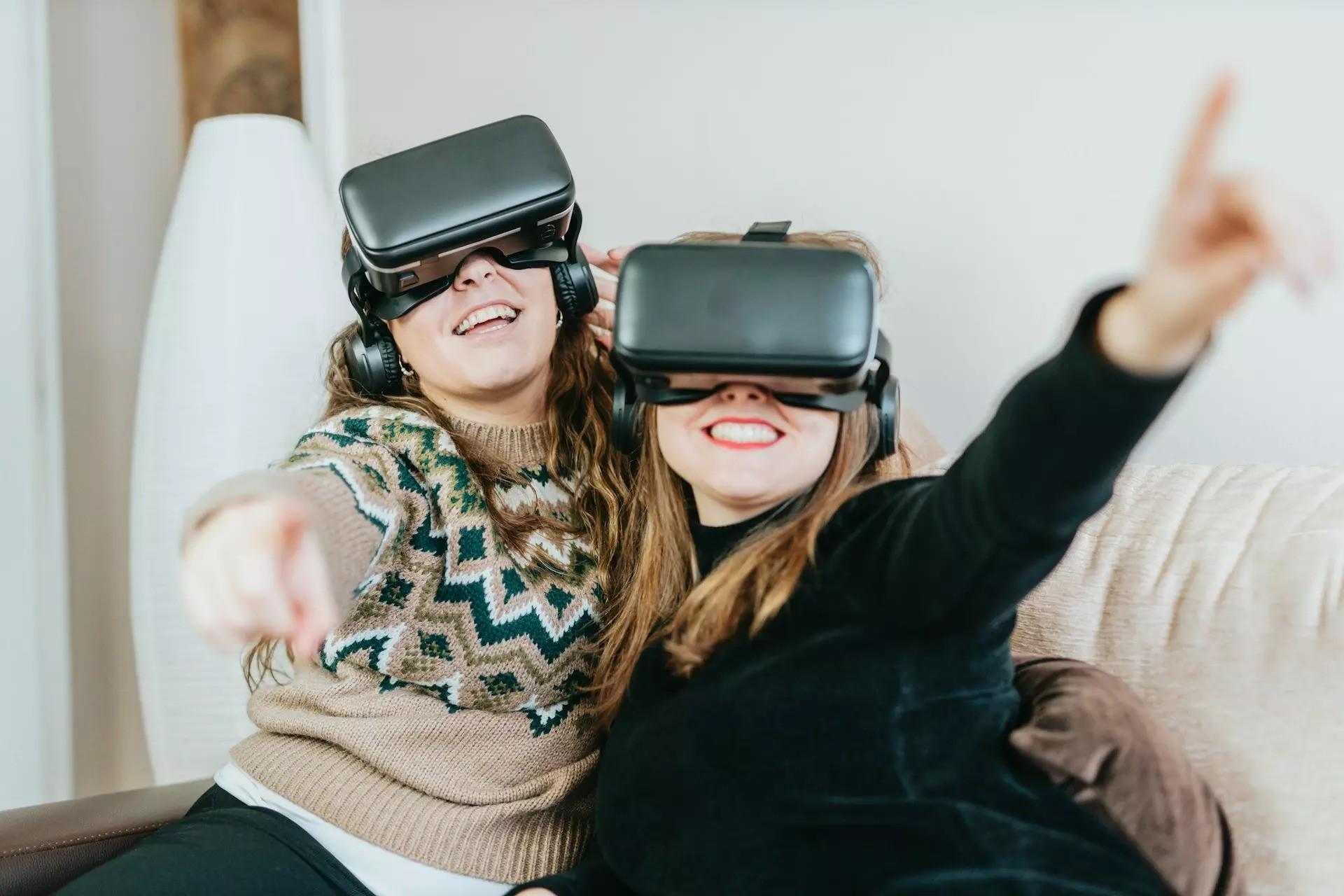 Two women sitting on a couch, with VR glasses on.