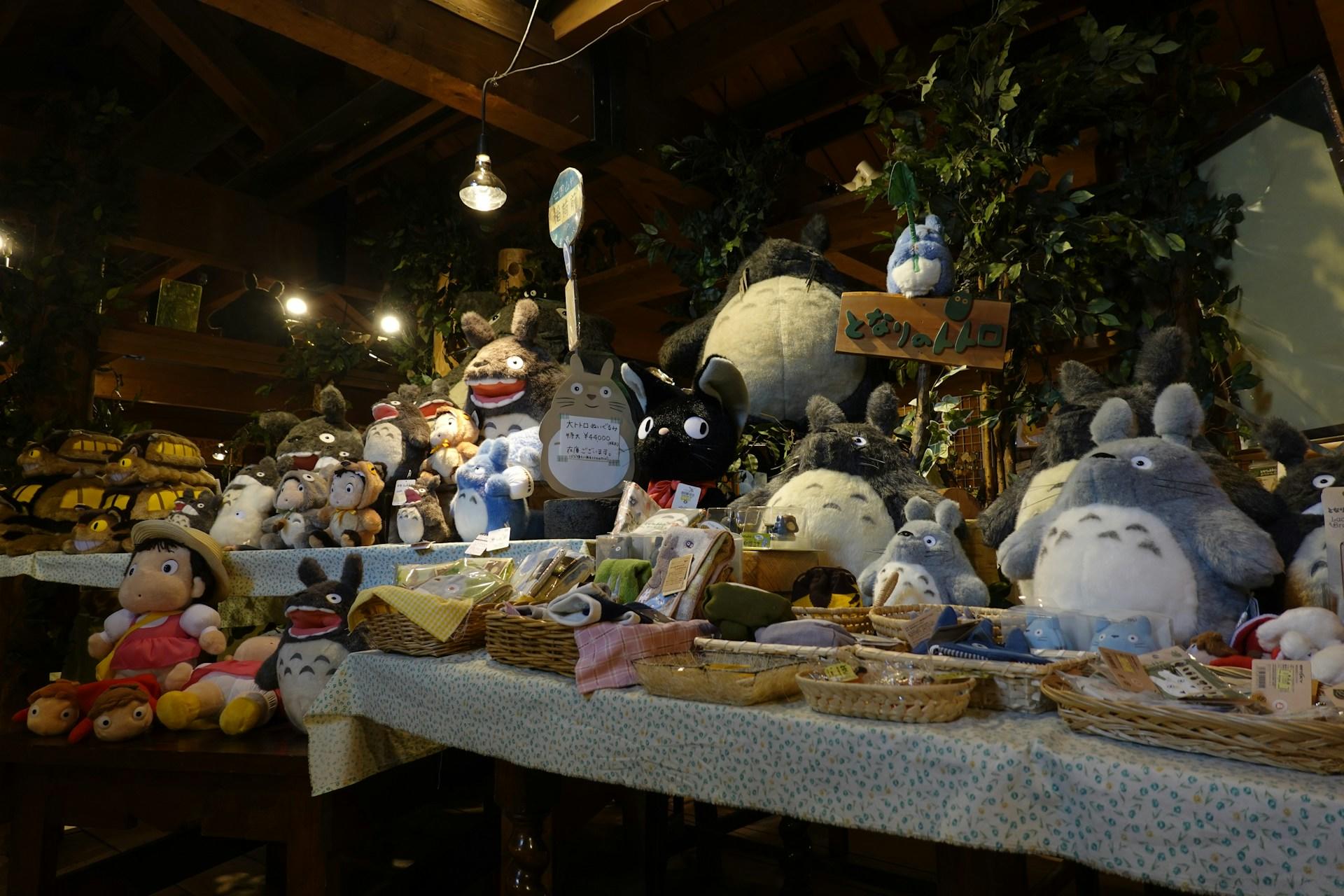 A table laden with plushie creatures set up on a street at night. 