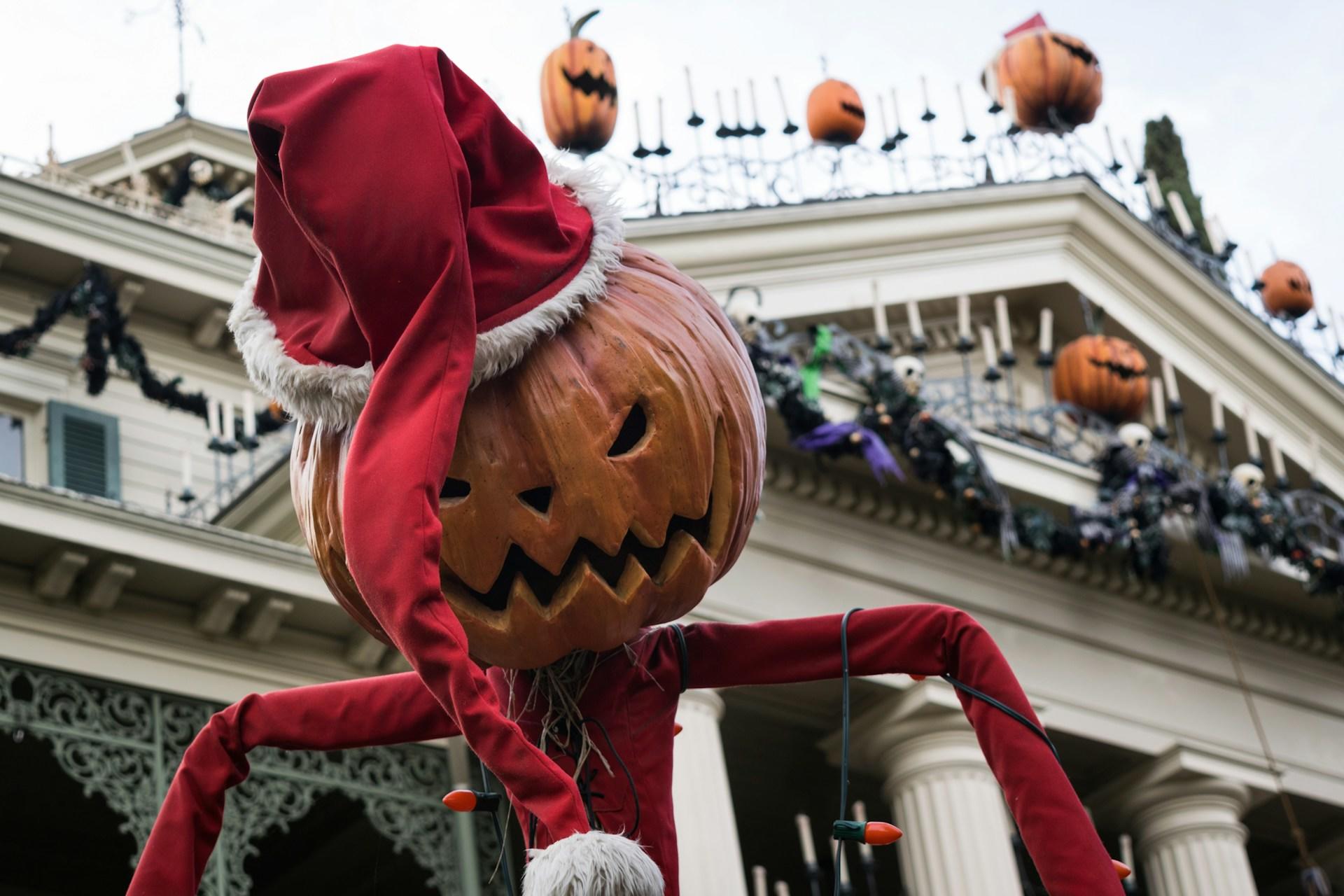 A home decorated for halloween with a pumpkin wearing a santa hat in the foreground.