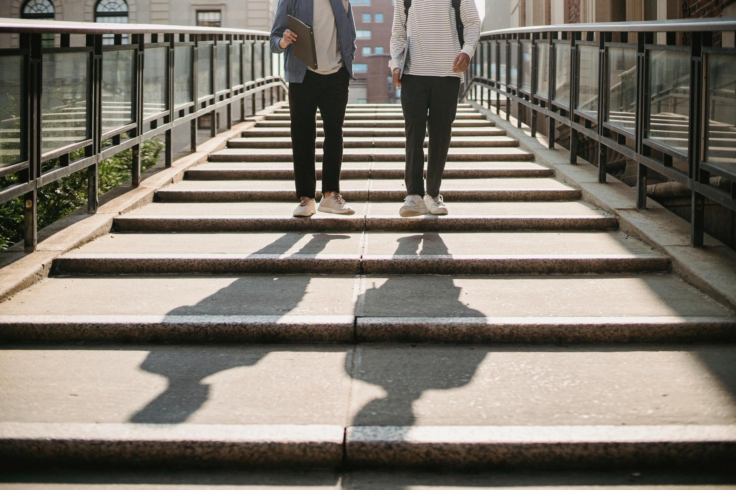 Two students walk in the school path as they contemplate whether to choose Law LLB or a BA Law degree. 