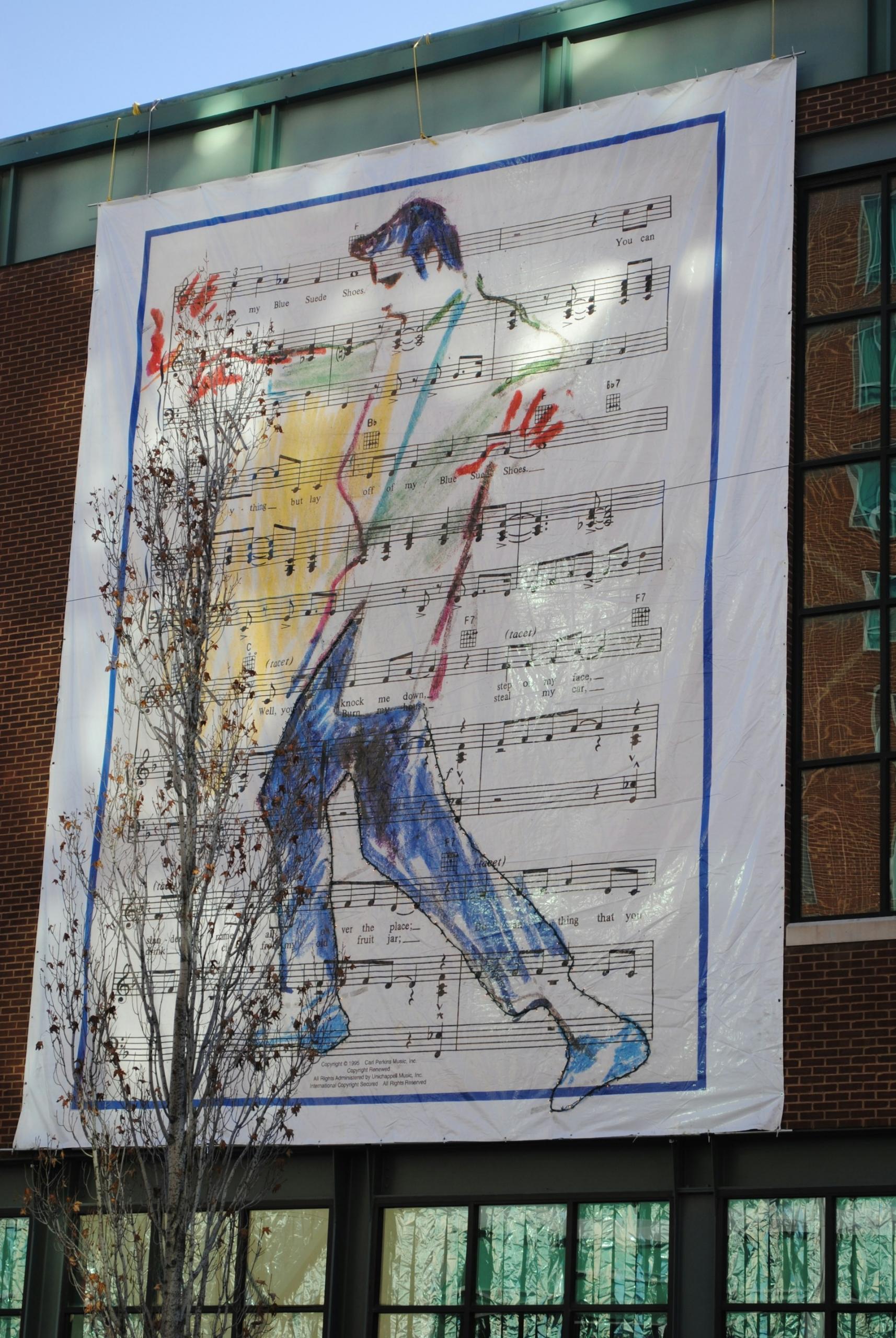A giant poster of Elvis drawn on a sheet of music. 