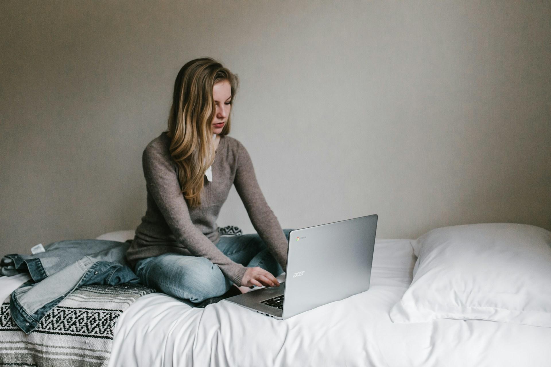 women working on laptop on bed