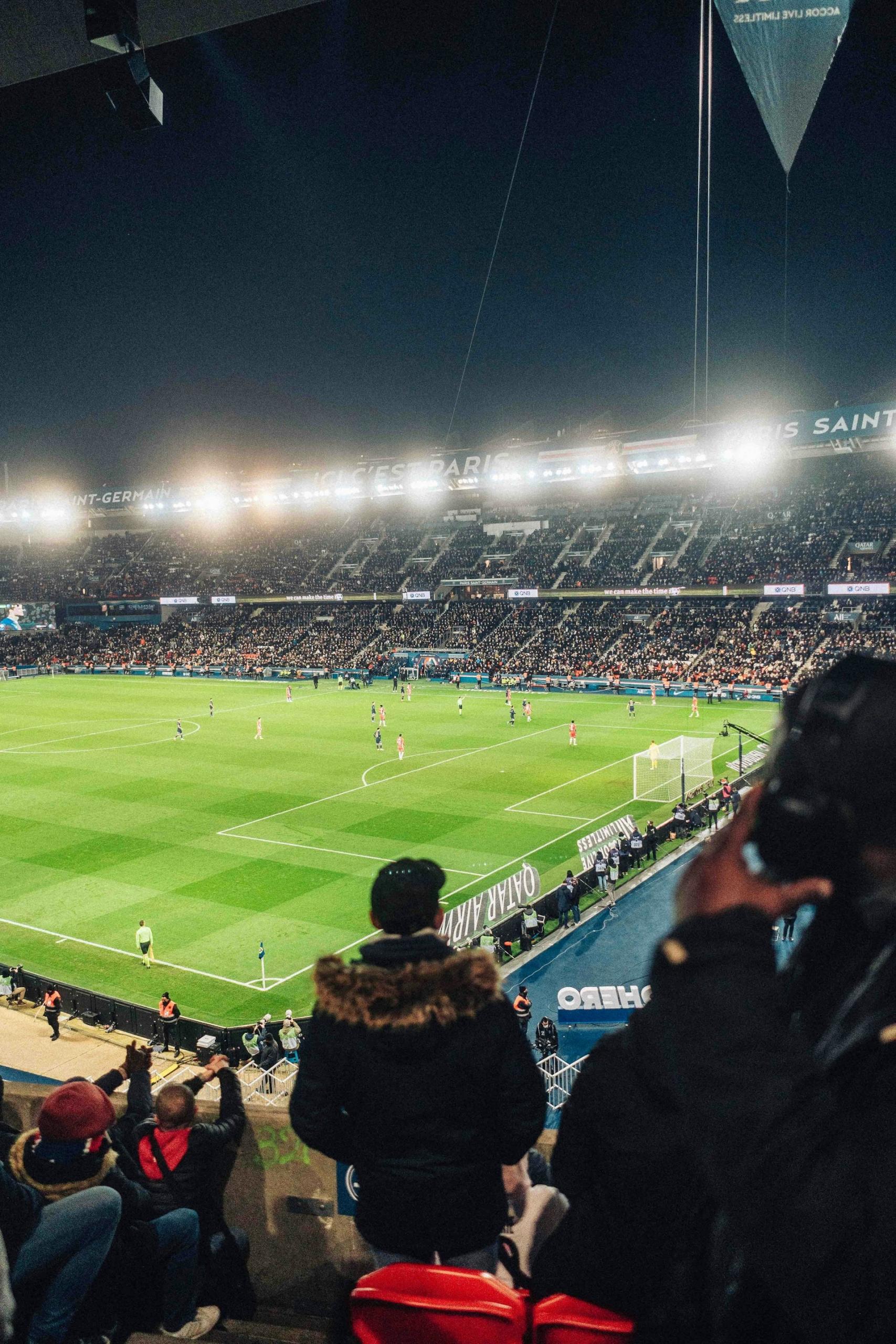 A lit up football pitch at night, with the stands full of fans.