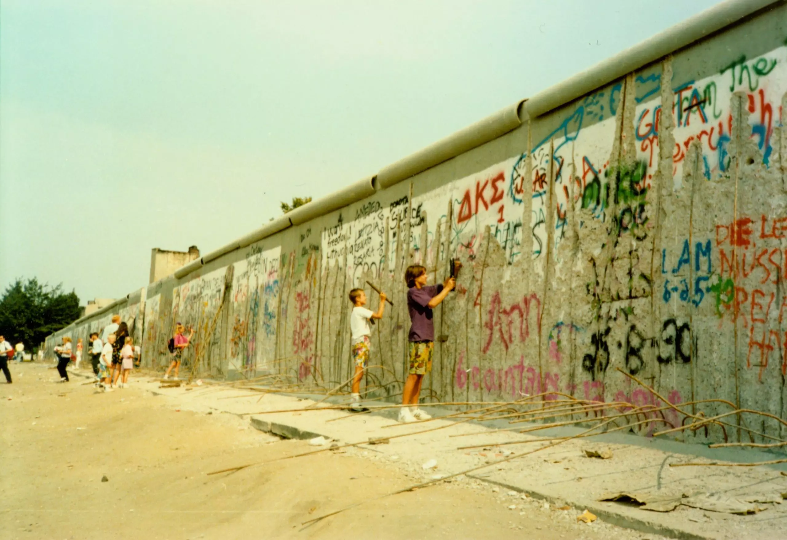 children standing beside the berlin wall