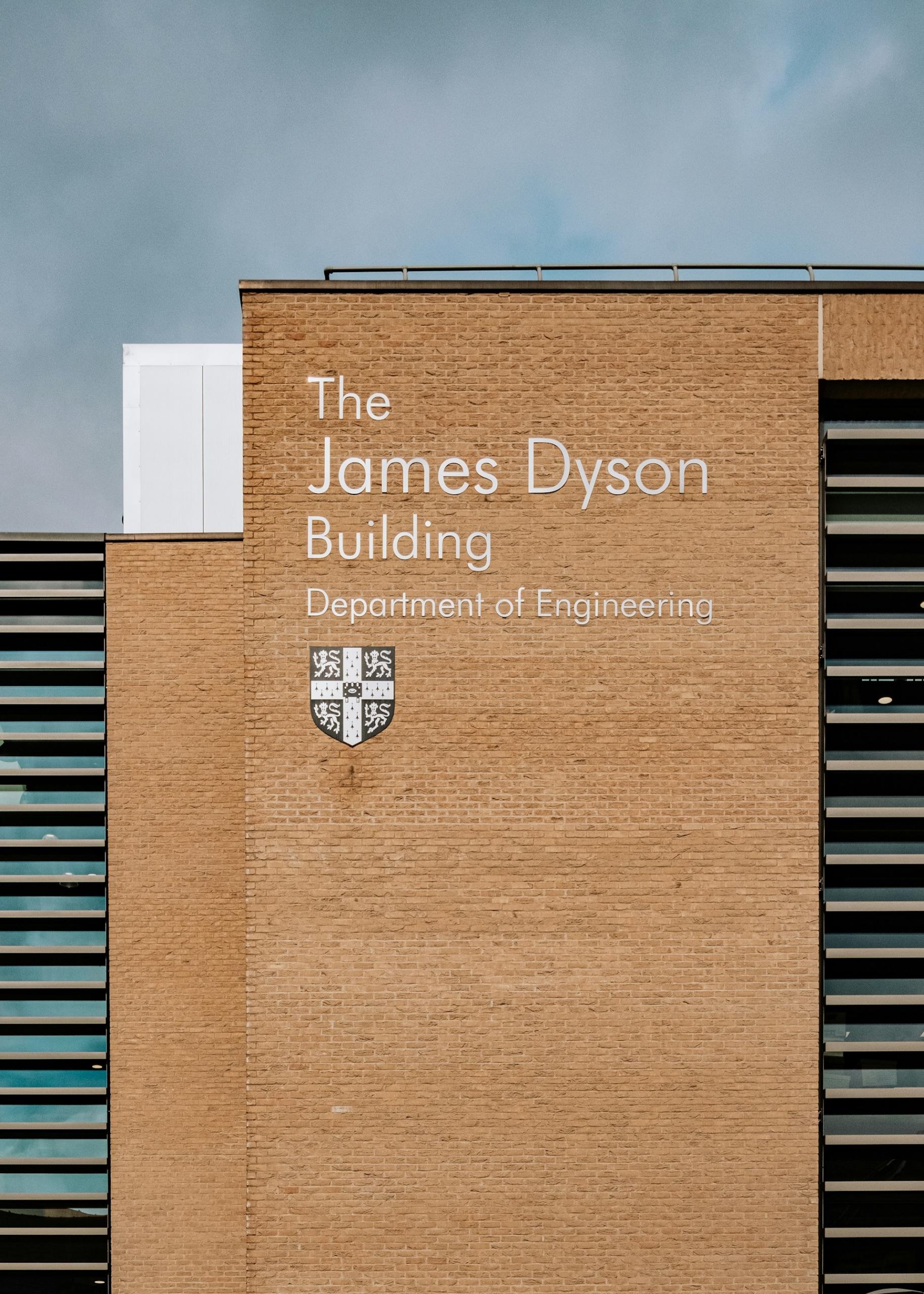 A yellow brick building with lettering on it on a cloudy day.