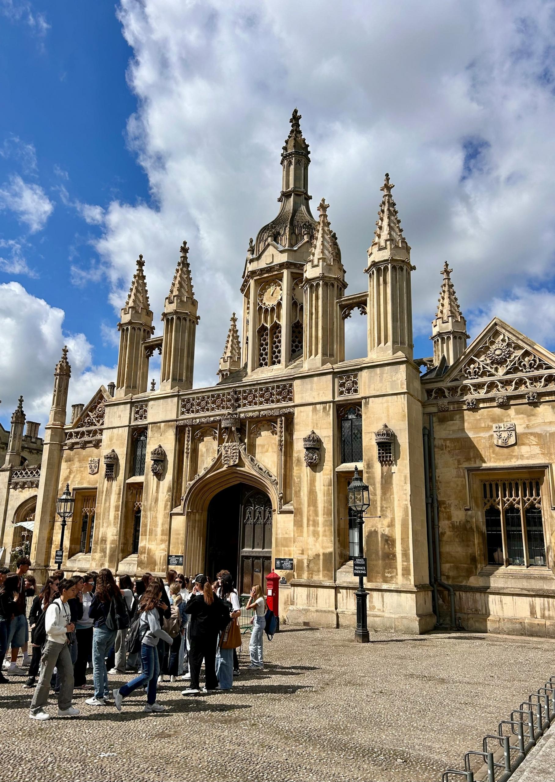 A large stone building with people in front of it on a sunny day.