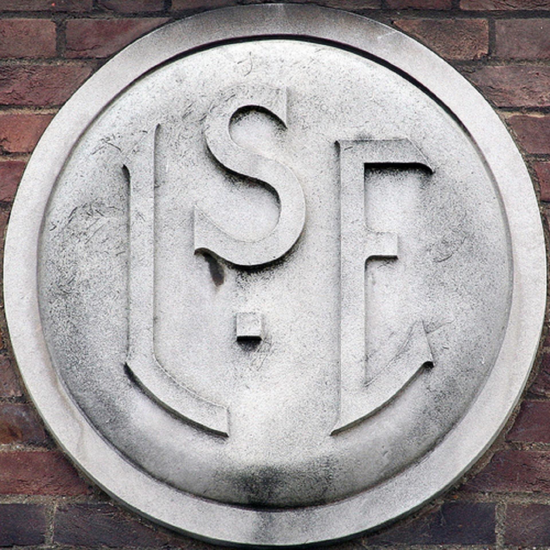 A grey stone engraving of LSE mounted on brick.