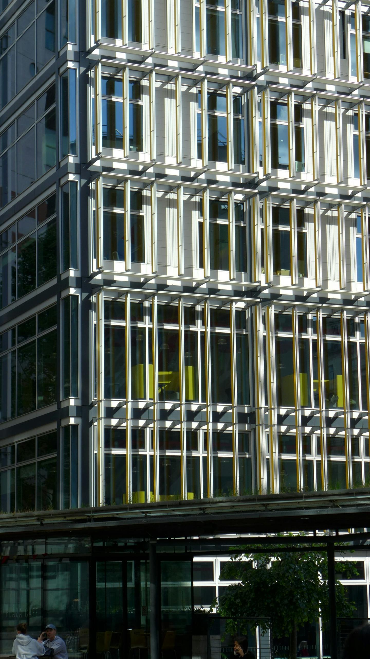 A tall building with white beams on its facade on a sunny day. 