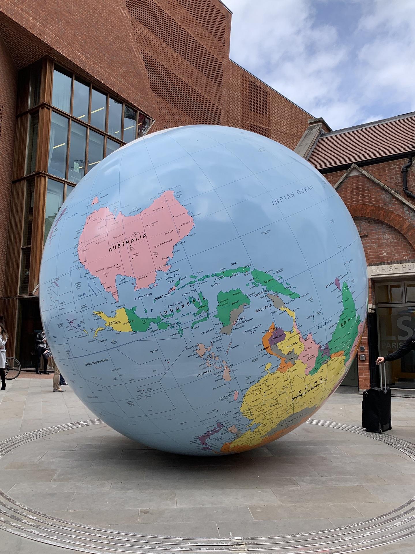An upside-down globe in front of a brick building.