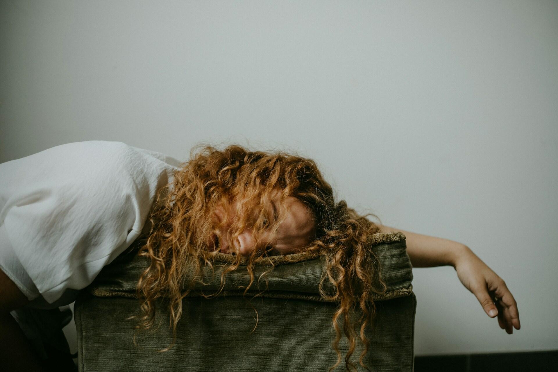 Person taking a power nap on an armchair indoors.