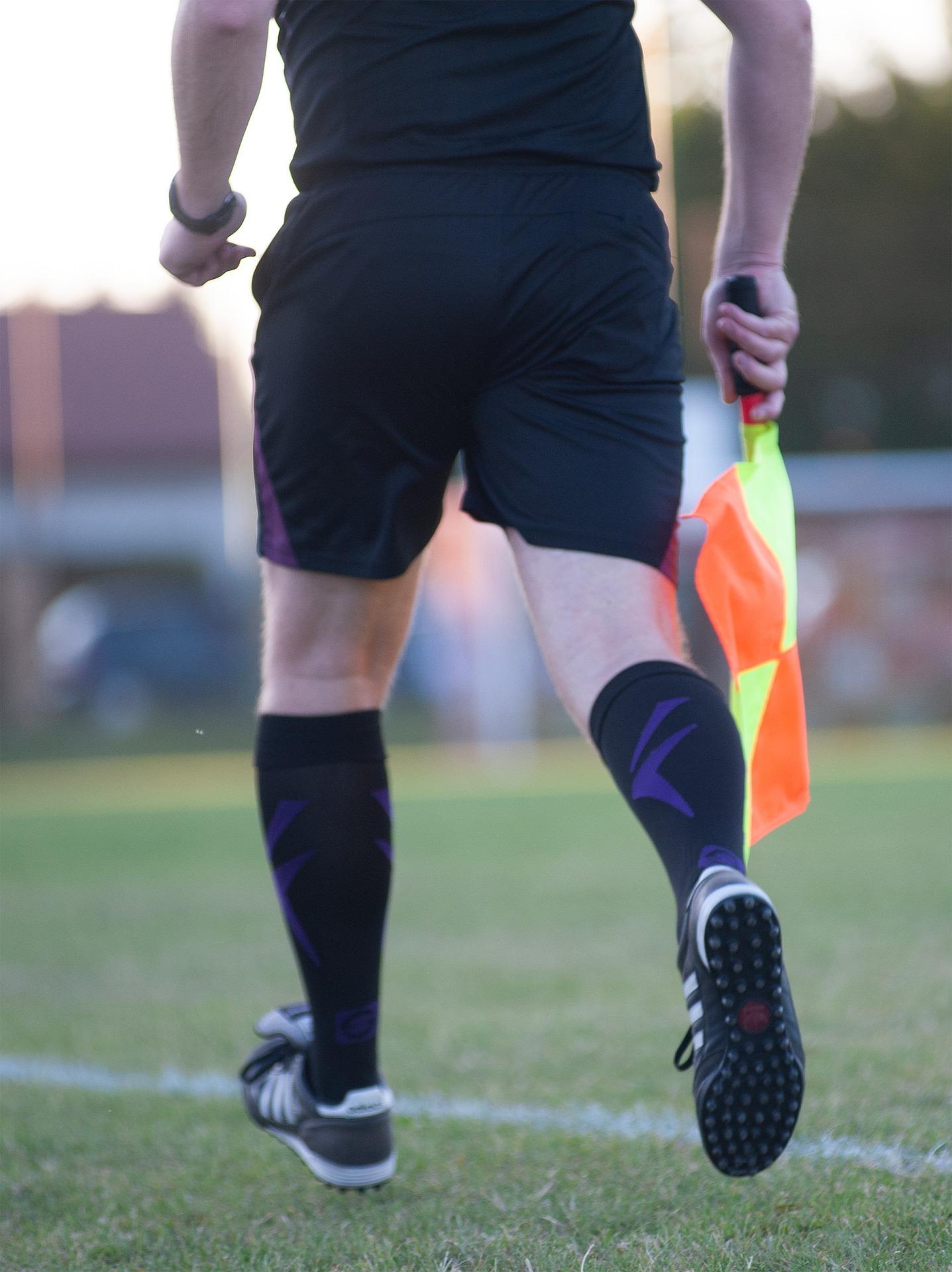 A person wearing black carries a yellow and orange flag.
