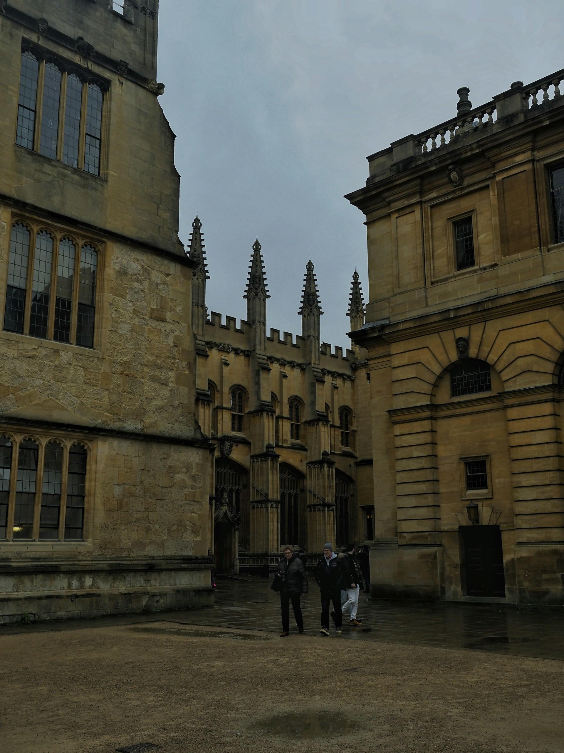 Three people in front of stone buildings on a cloudy day. 