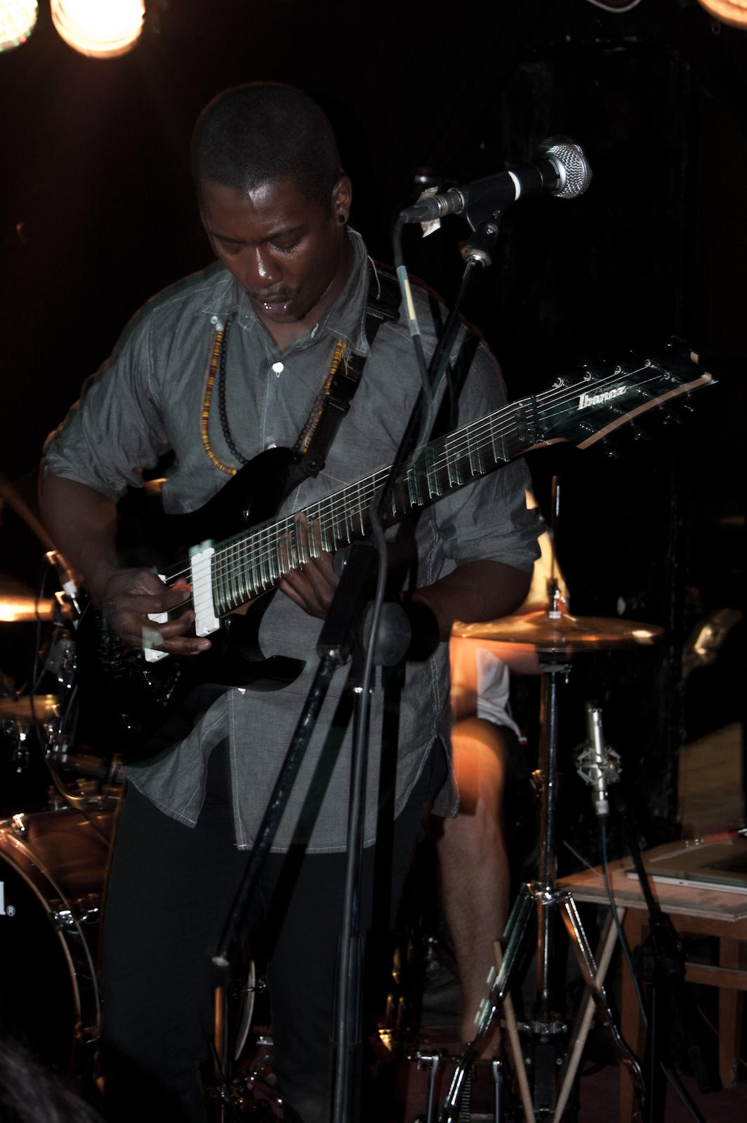 A man plays an 8-string guitar on stage. 