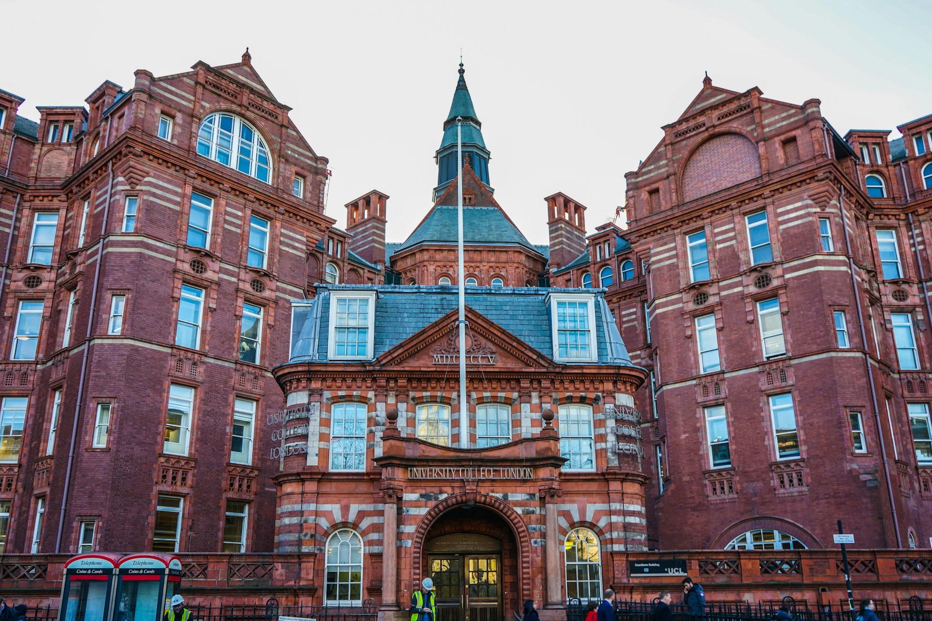 A large red brick building topped with a spire on a cloudy day.