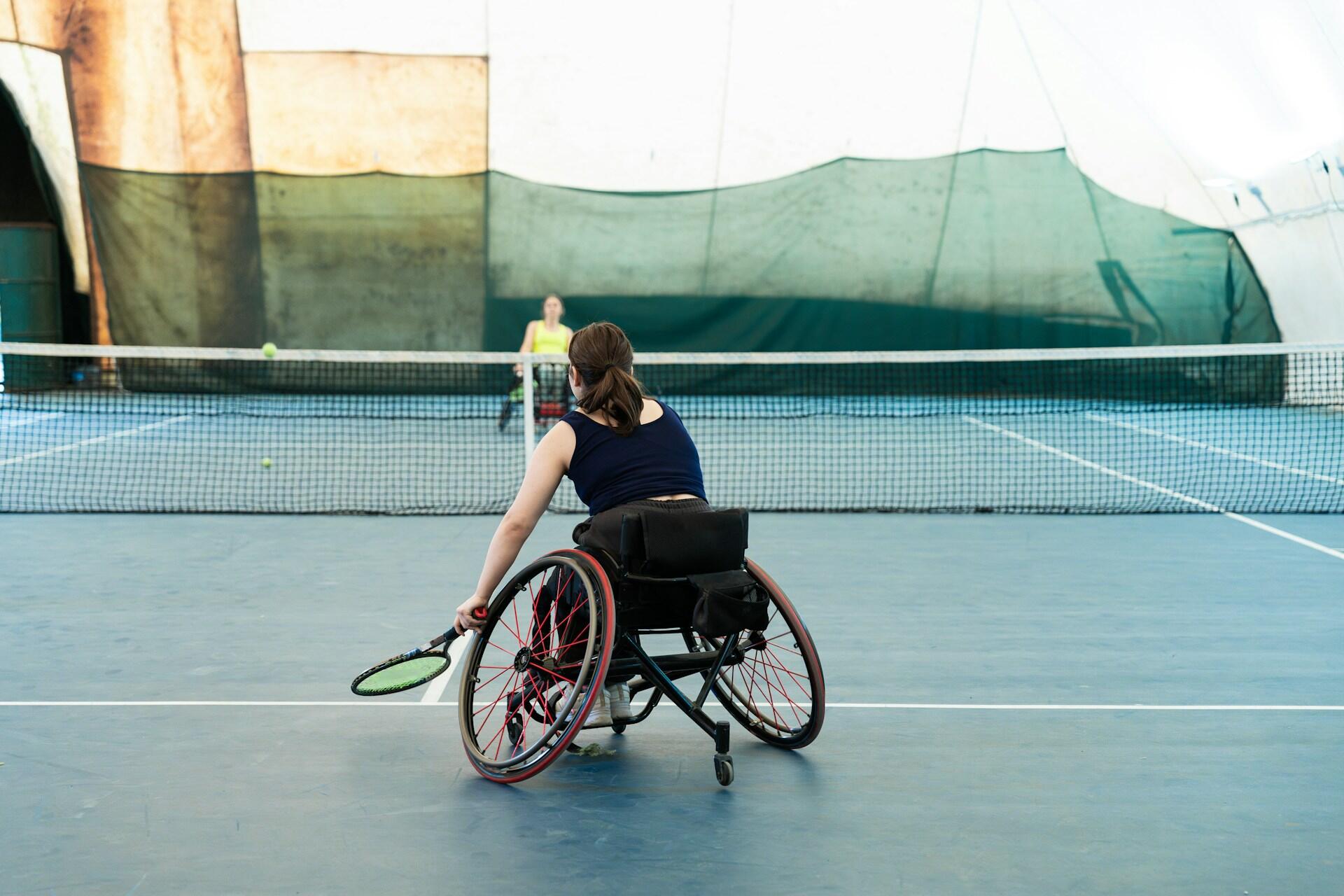 Two wheelchair tennis players facing off across the net. 