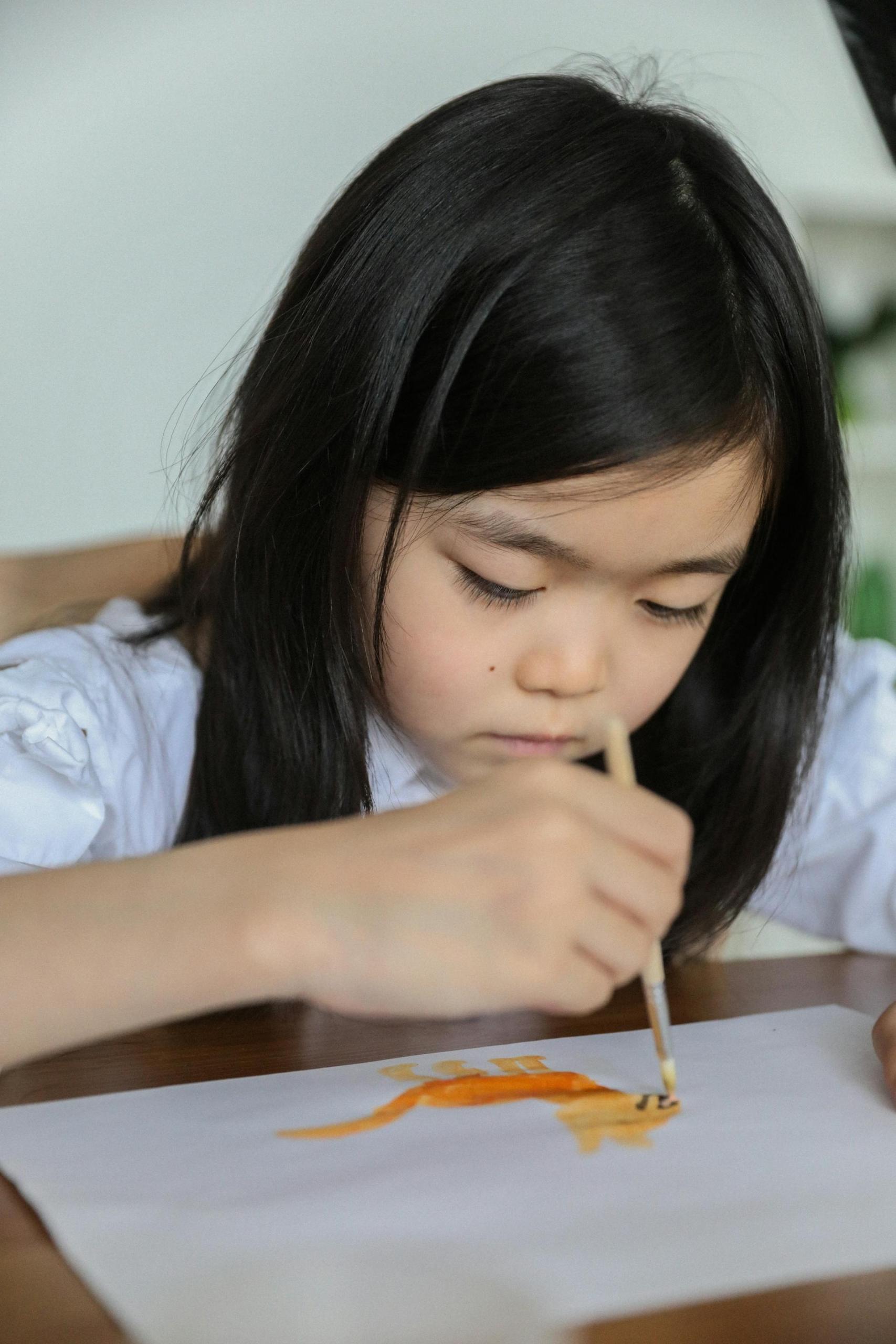 A young girl sat at a table drawing a picture.