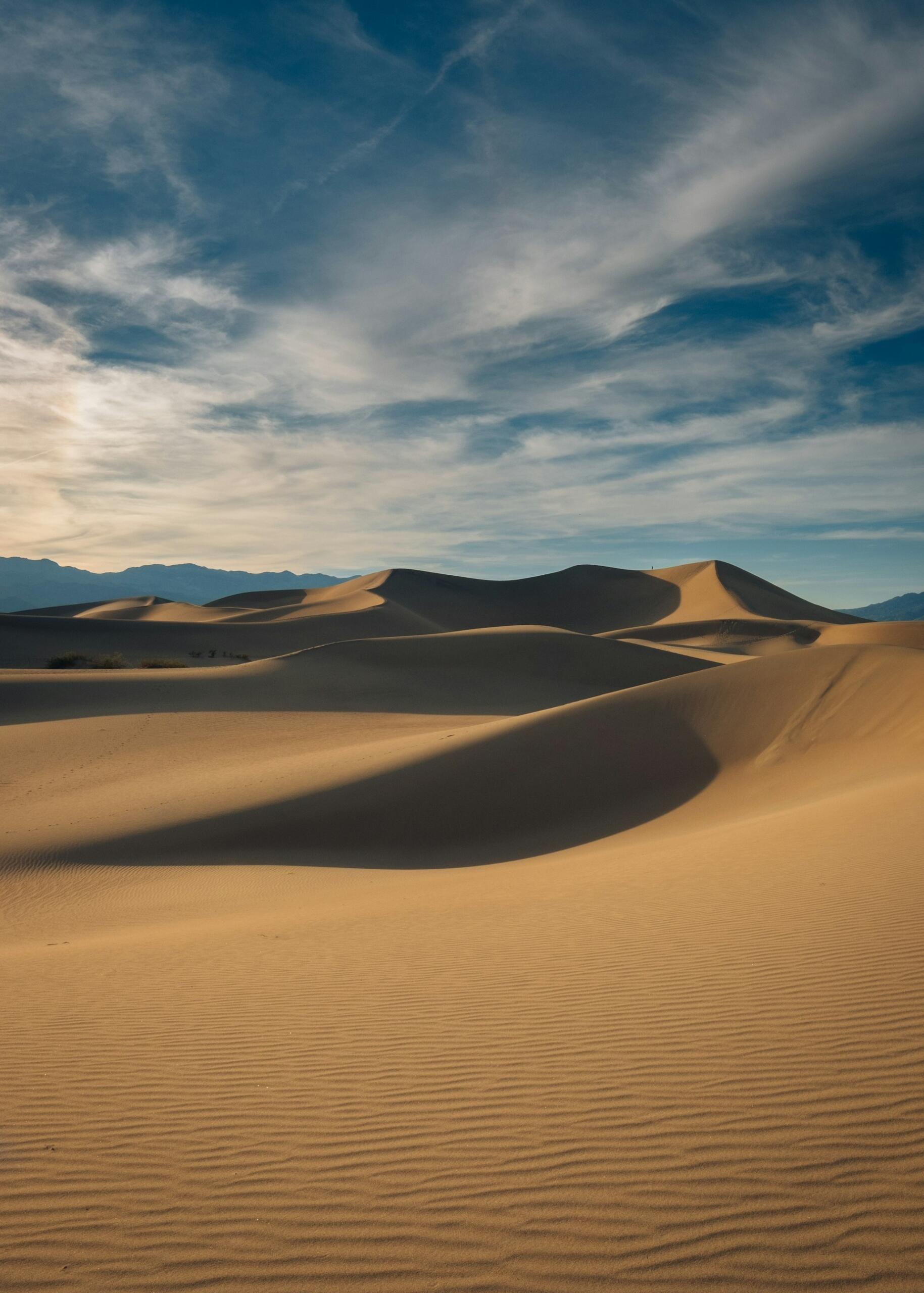 A sand desert with a mildly cloudy sky.