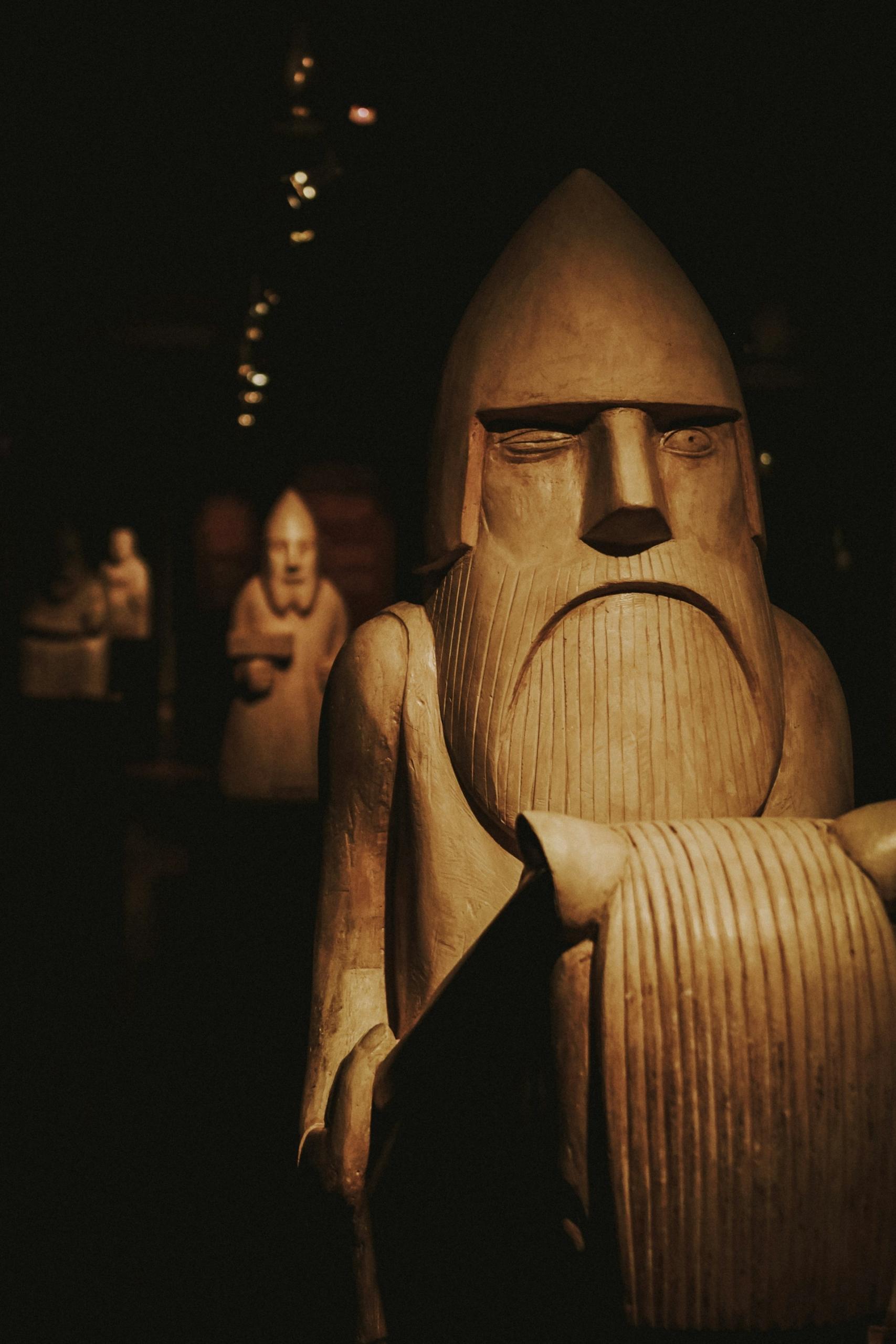 Wooden carvings of bearded men with pointy heads astride horses. 