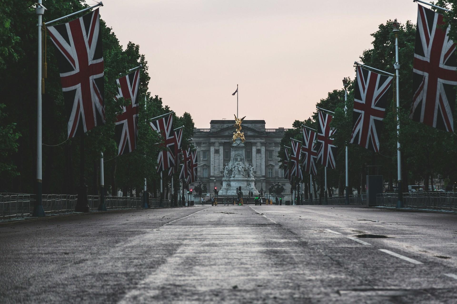 An empty street lined with British flags, and a statue at the end of it.