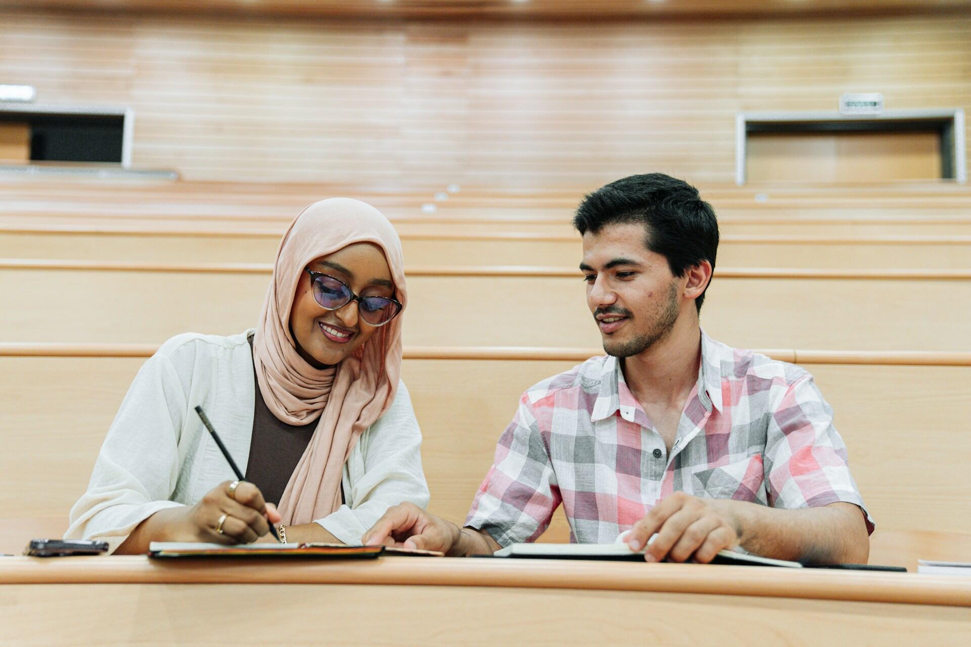 Two people sitting side by side in a lecture hall.
