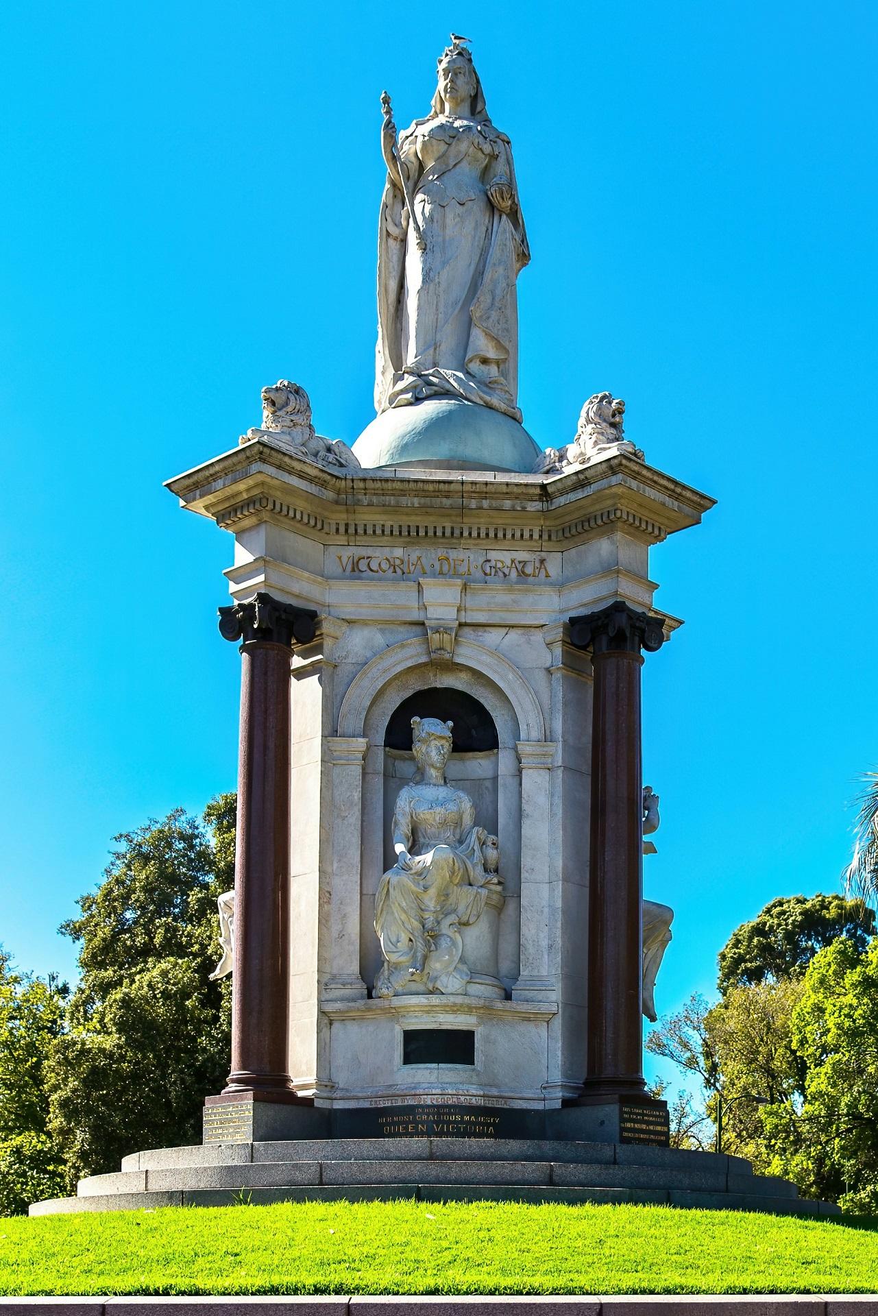 A white stone statue on a grassy knoll on a sunny day.