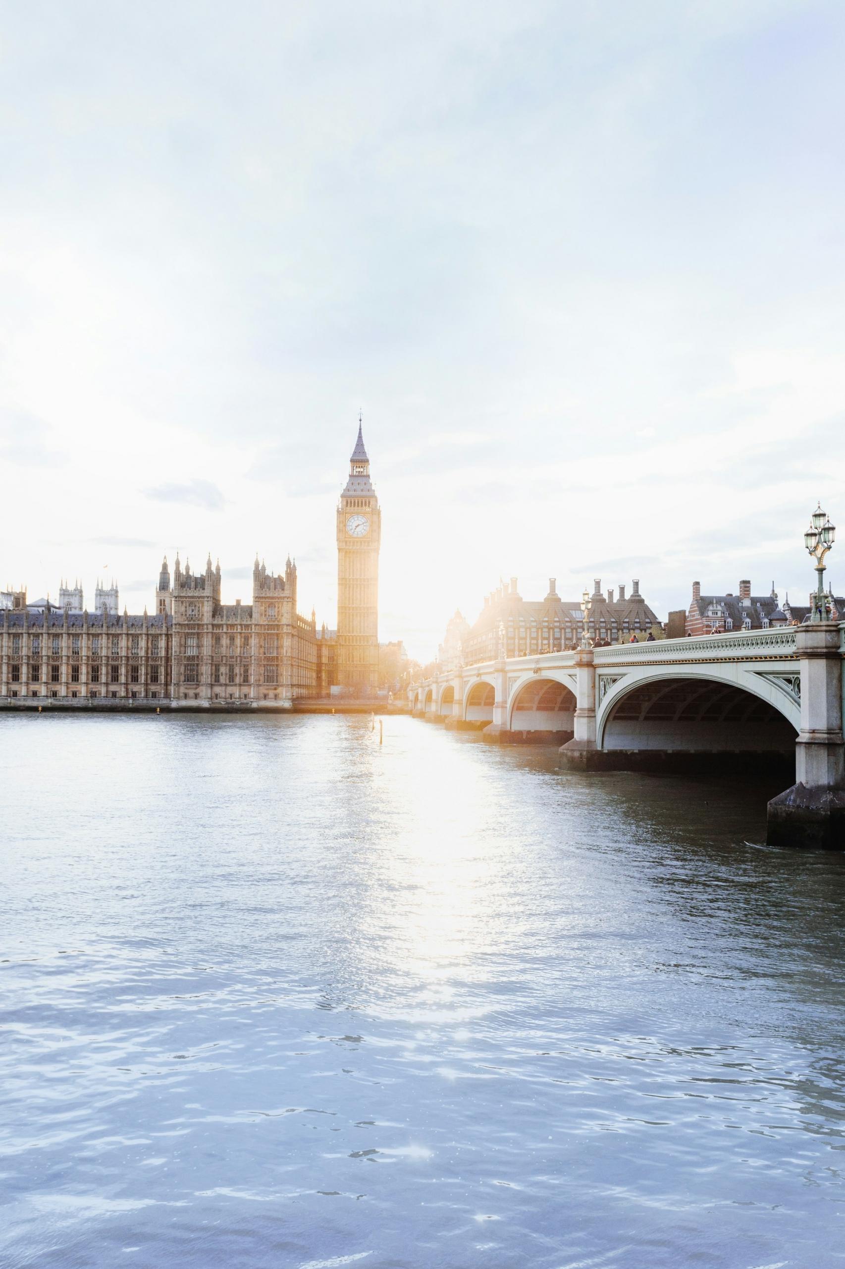 A stone bridge, the Thames, and Parliament at sunrise 