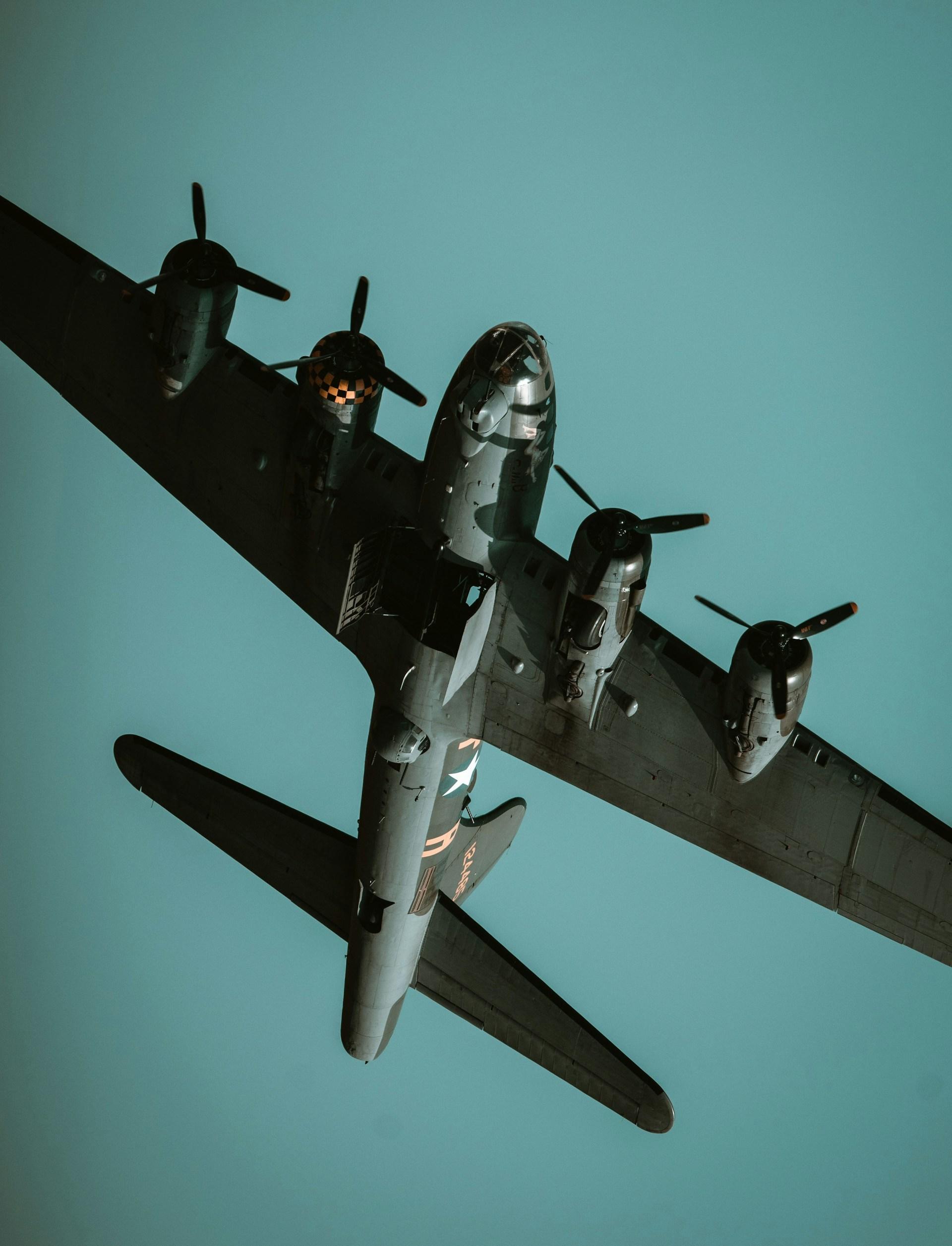 A four-engine propeller plane against a blue sky. 
