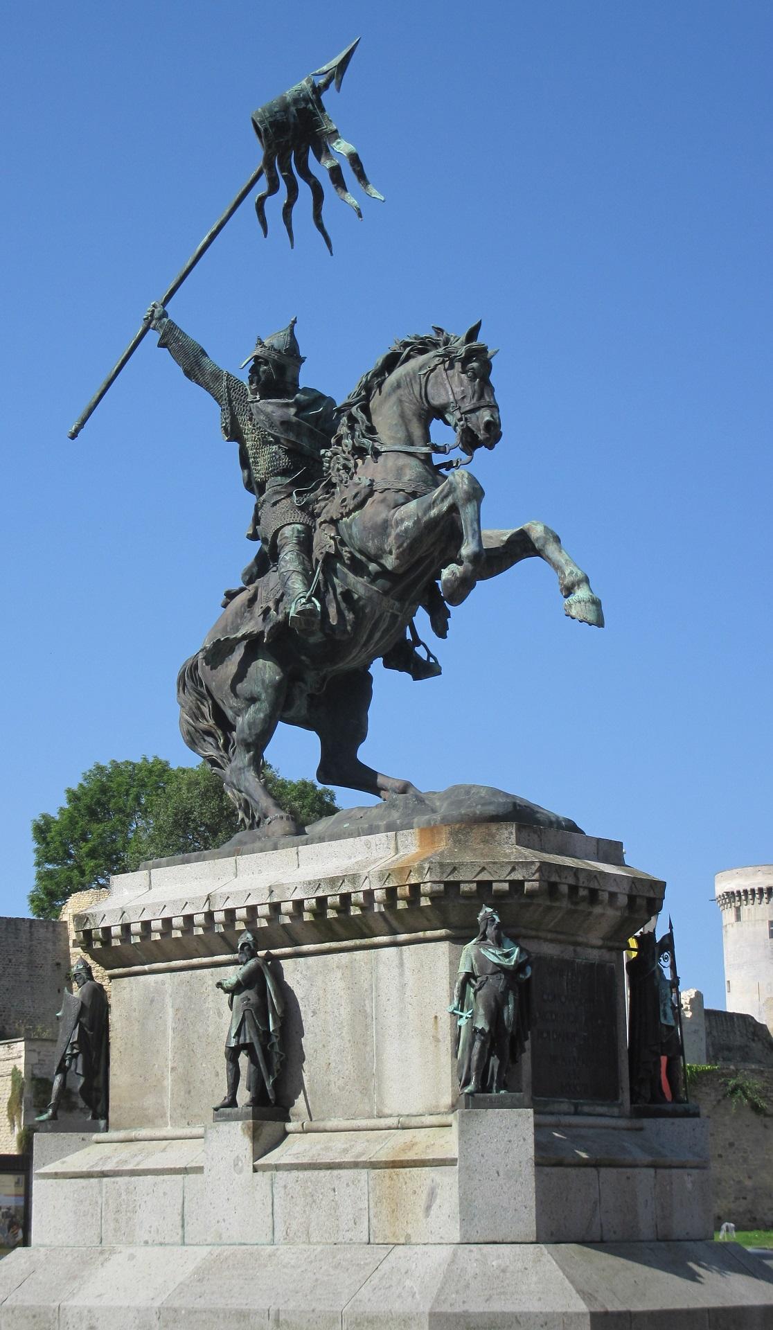 A statue of a man on a horse holding a banner aloft on a sunny day. 