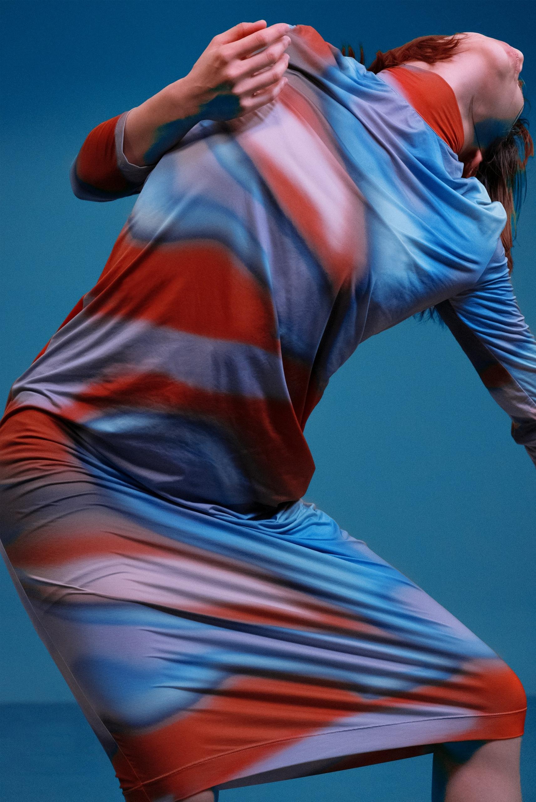 A woman in a psychidelic dress dances.