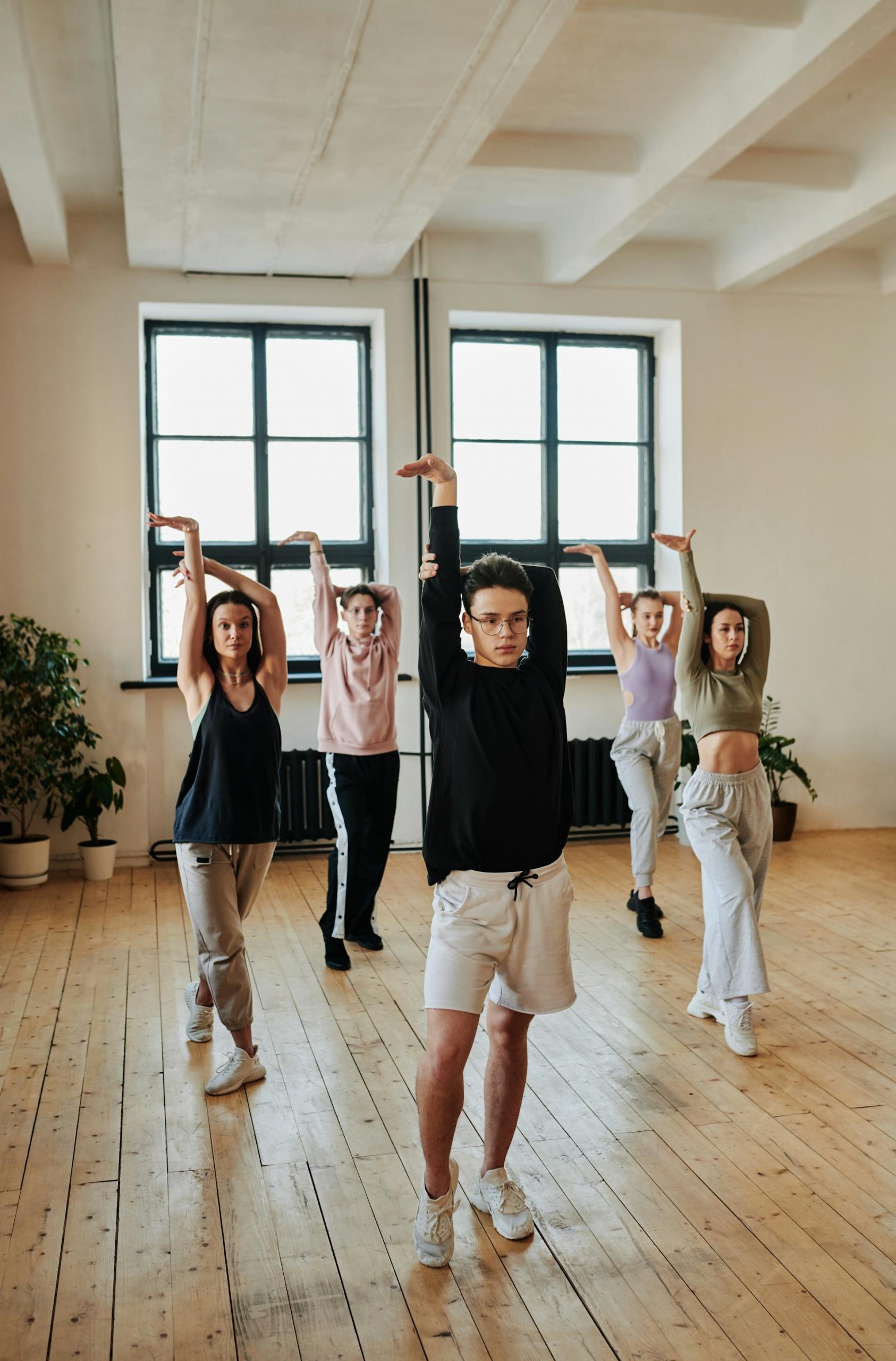 Five children hold a dance pose in a brightly-lit studio.