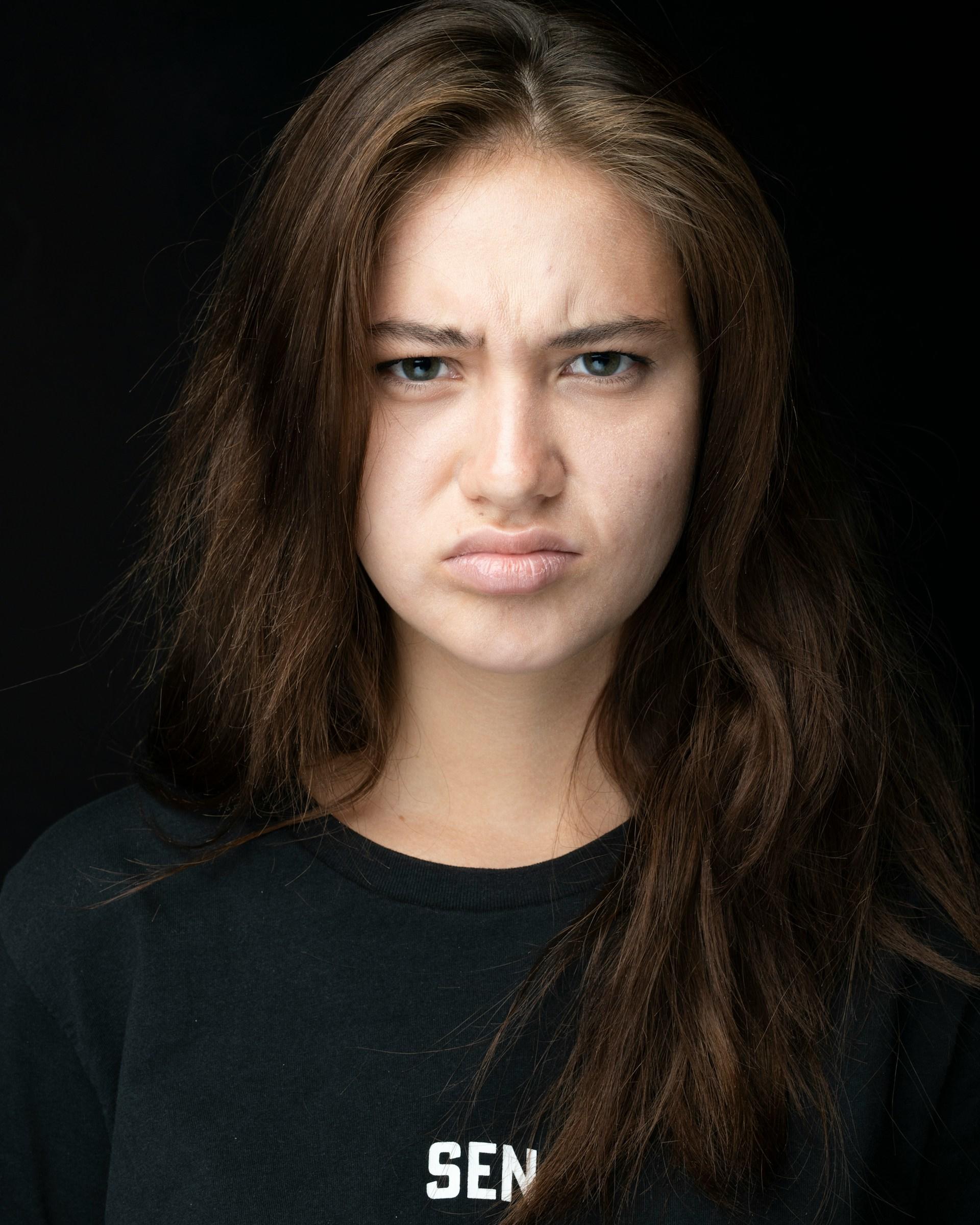 A woman in a black tee-shirt looks angry.