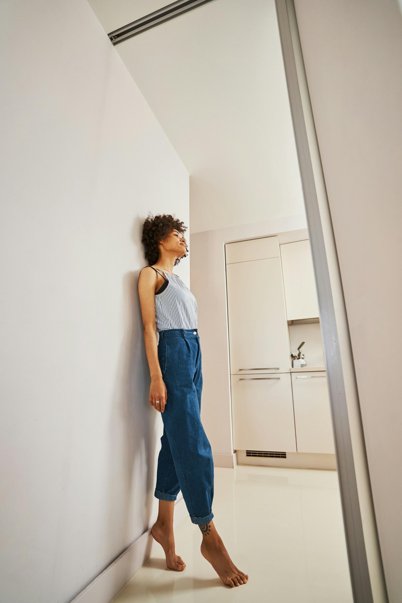 A woman stands on tiptoe while leaning against a wall. 