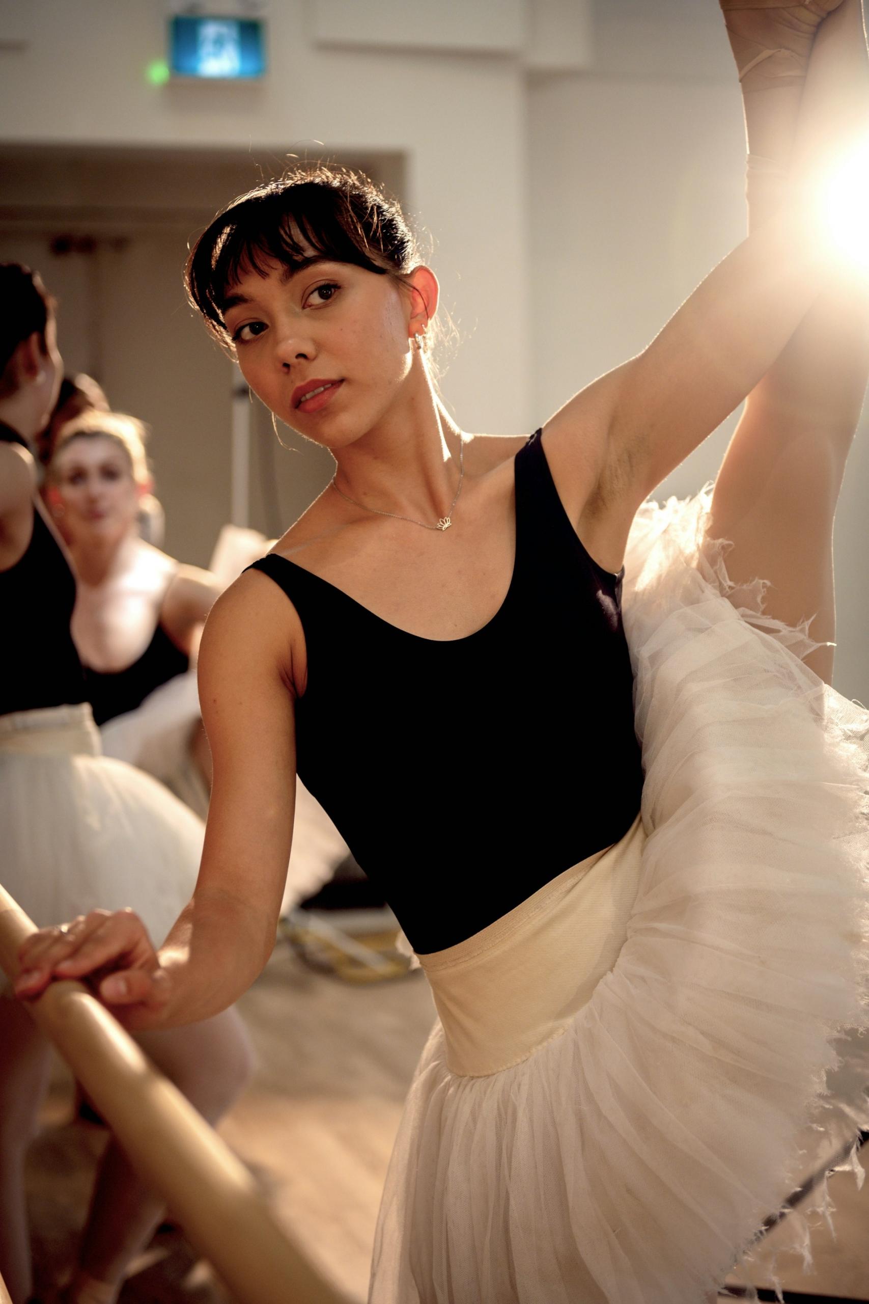 A woman wearing dance clothing looks uncertain as she poses.