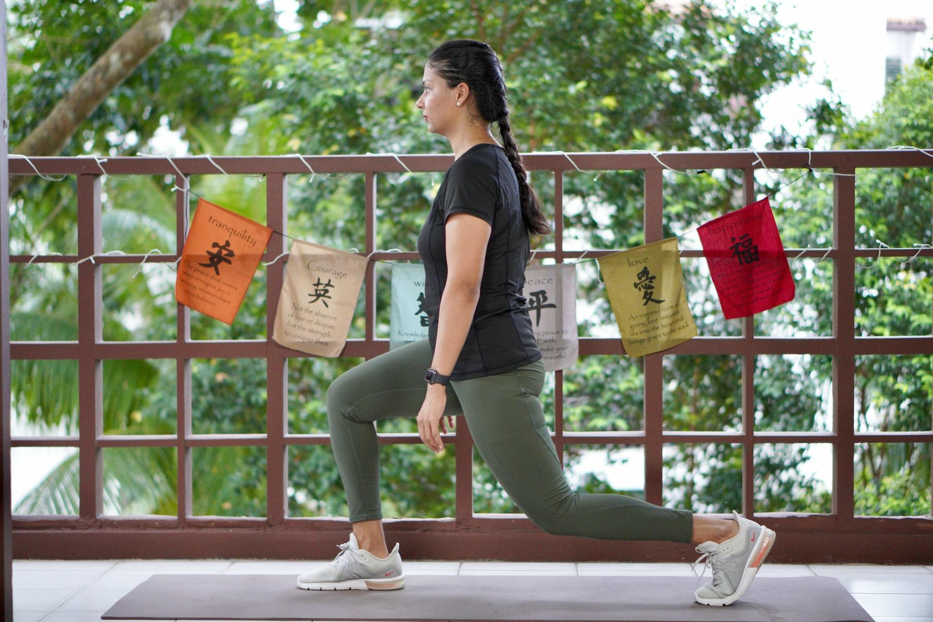 A woman wearing sports attire does a lunge outdoors on a cloudy day. 