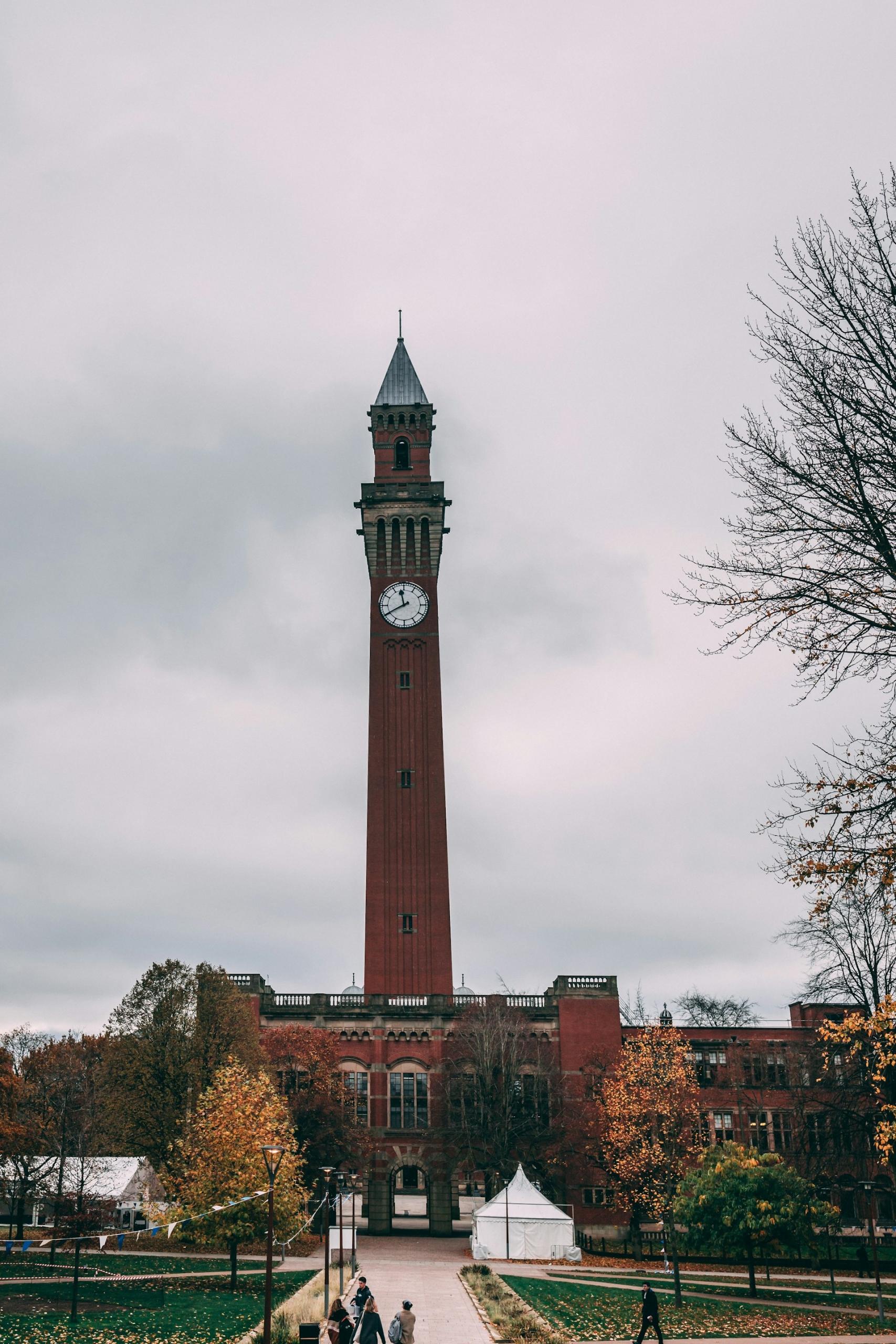 A tall thin red brick tower on a cloudy day. 