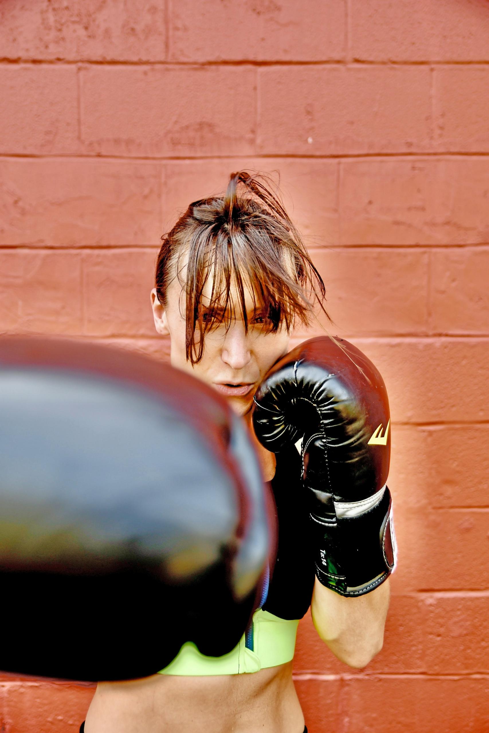 A woman with black boxing gloves throws a punch.