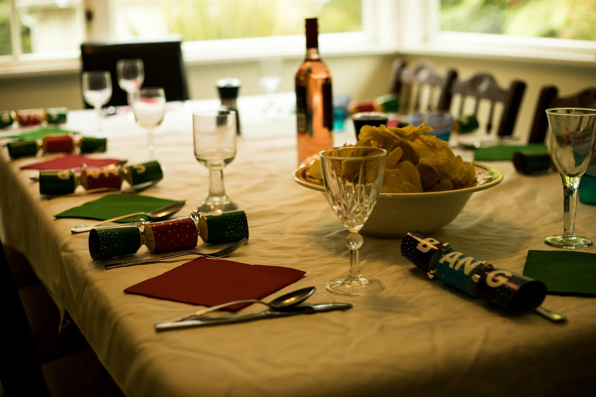 A table laid for Christmas including crackers, cutlery, and wine.