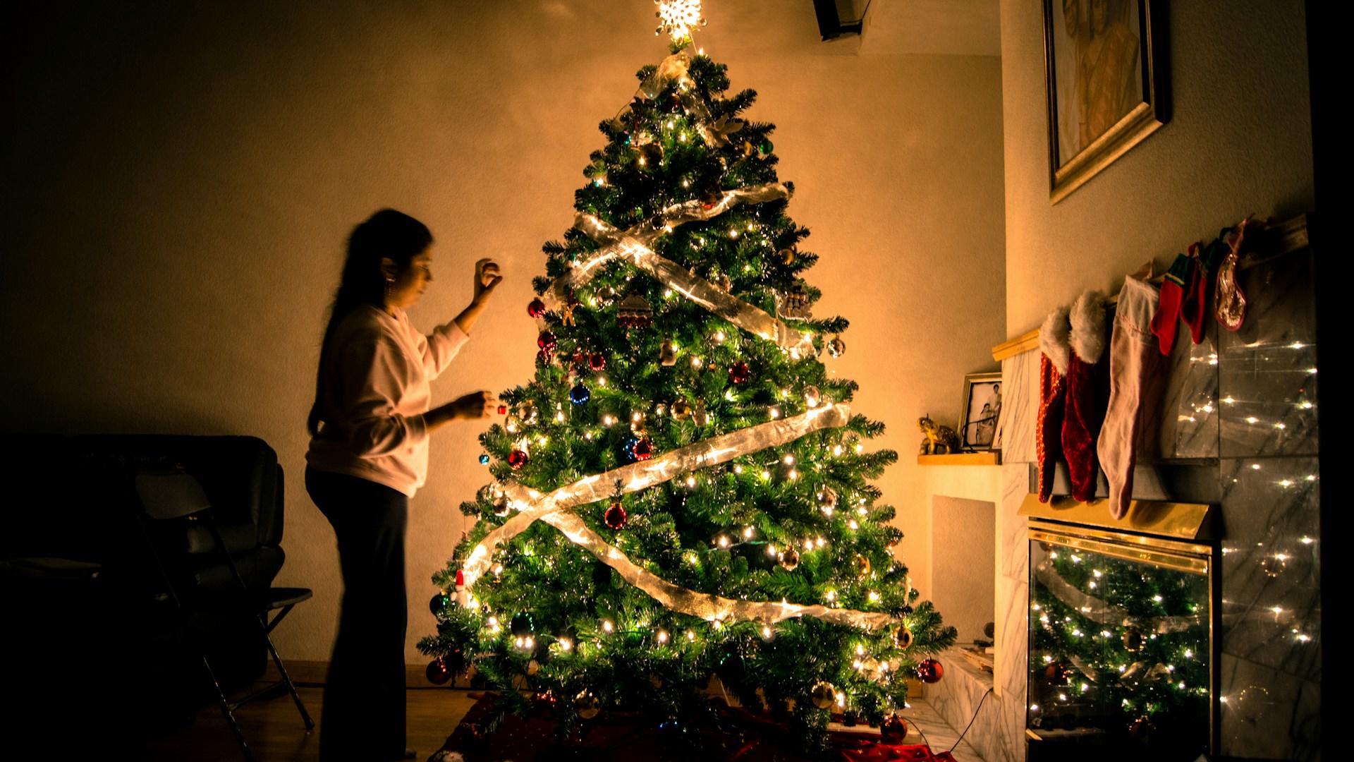 A young girl next to an illuminated Christmas tree