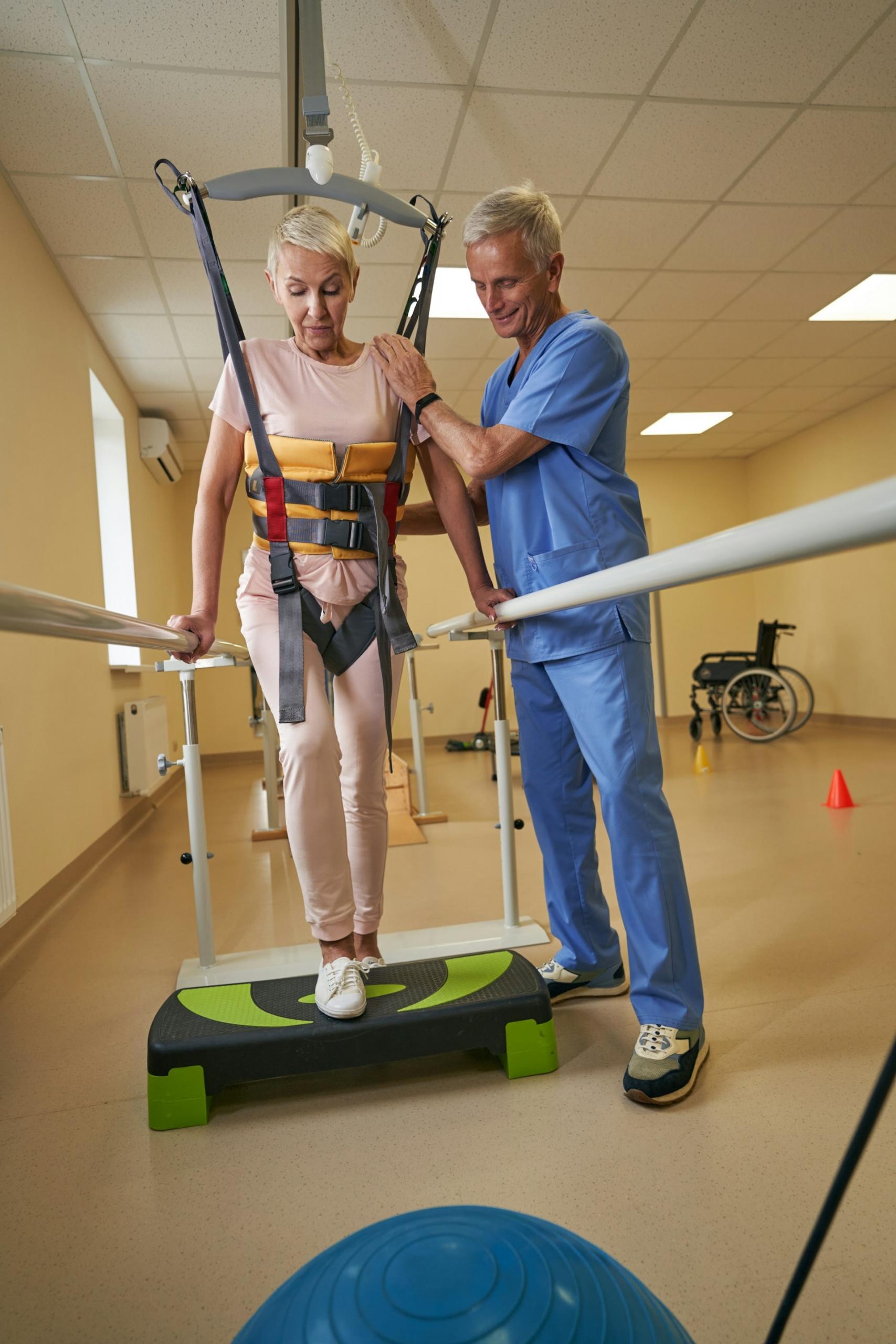 A woman in a harness stepping onto an aerobics block.
