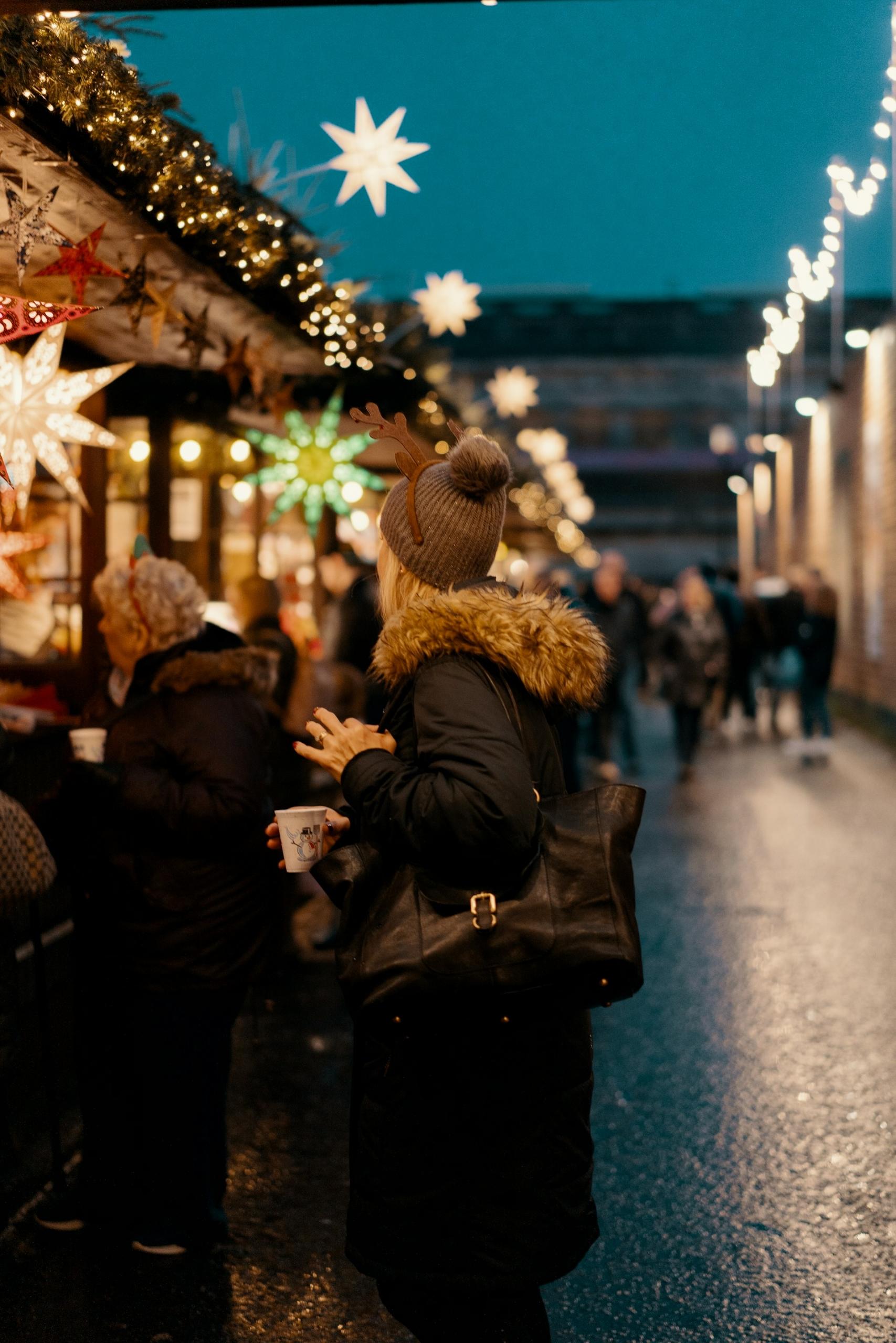 Stalls at Edinburgh Christmas Market wiht people walking around.